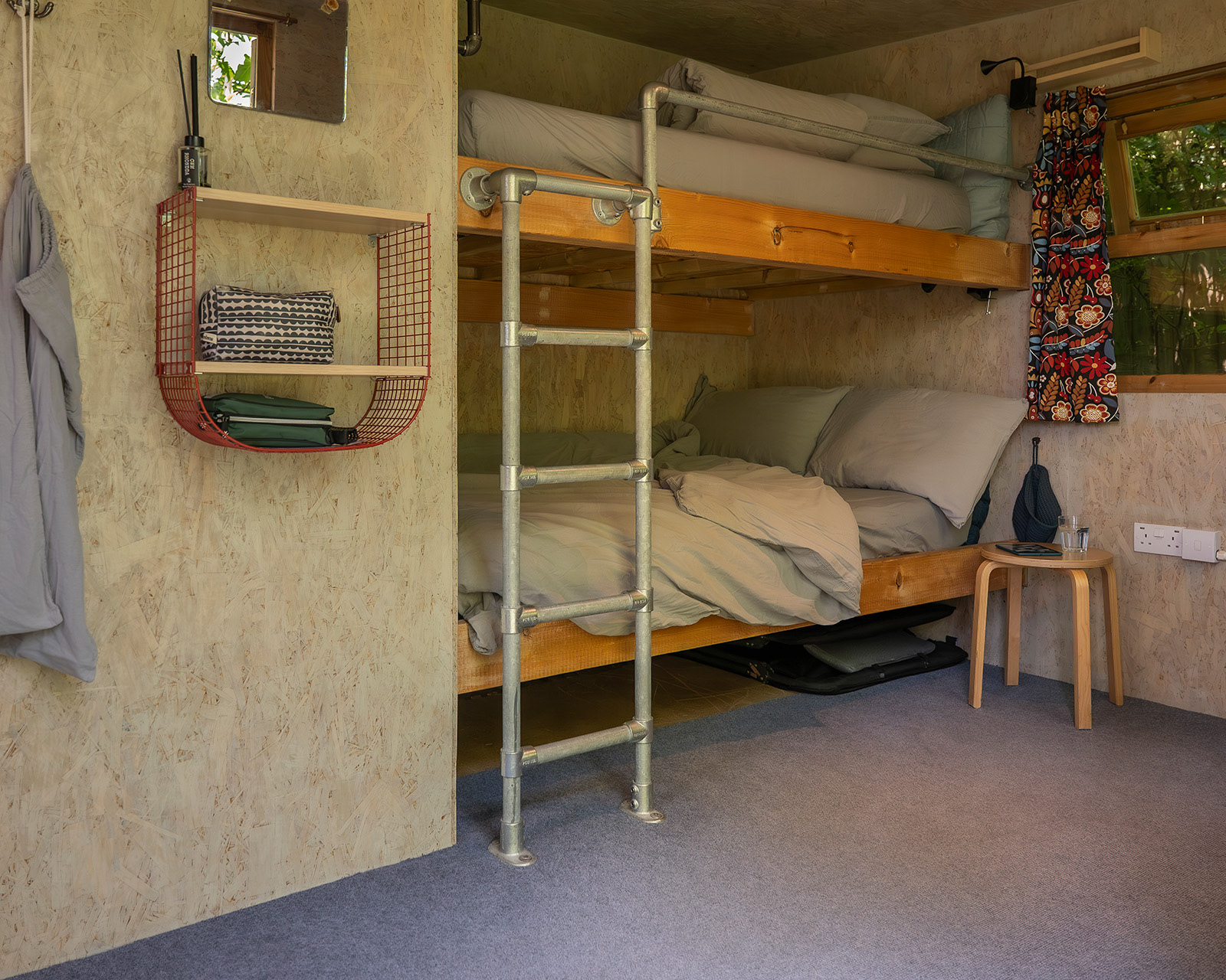 The bunk bed inside Gwynfa cabin at Roost Merthyr Tydfil, with a slightly rumpled duvet, small shelf and cloth bag adding to the cosy, lived-in feel. A welcoming sleeping space for guests enjoying a South Wales glamping stay.