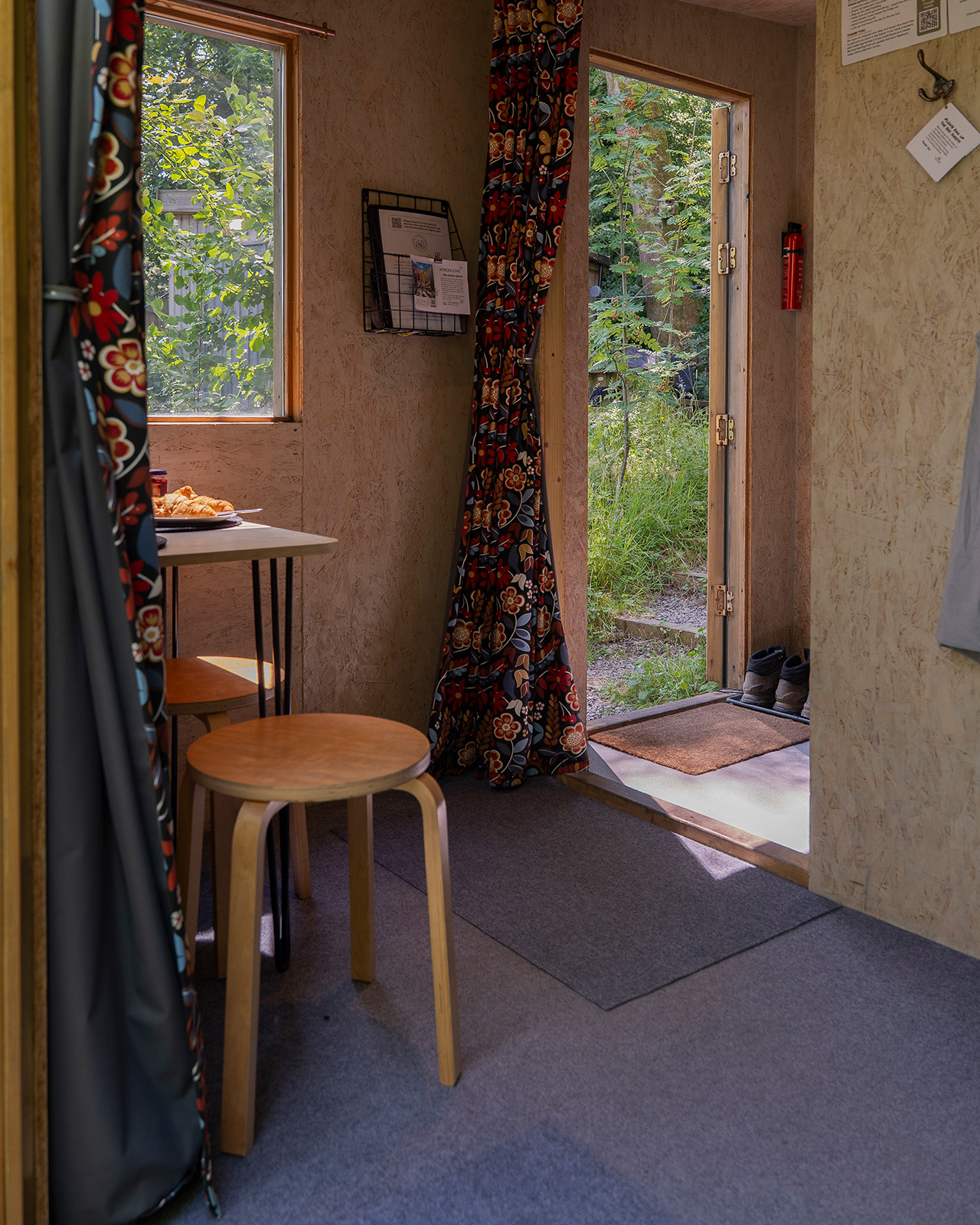 A view into Gwynfa cabin at Roost Merthyr Tydfil through the open entrance, showing the dining area and main doorway. The welcoming interior and natural setting create a relaxed atmosphere for a South Wales glamping stay.