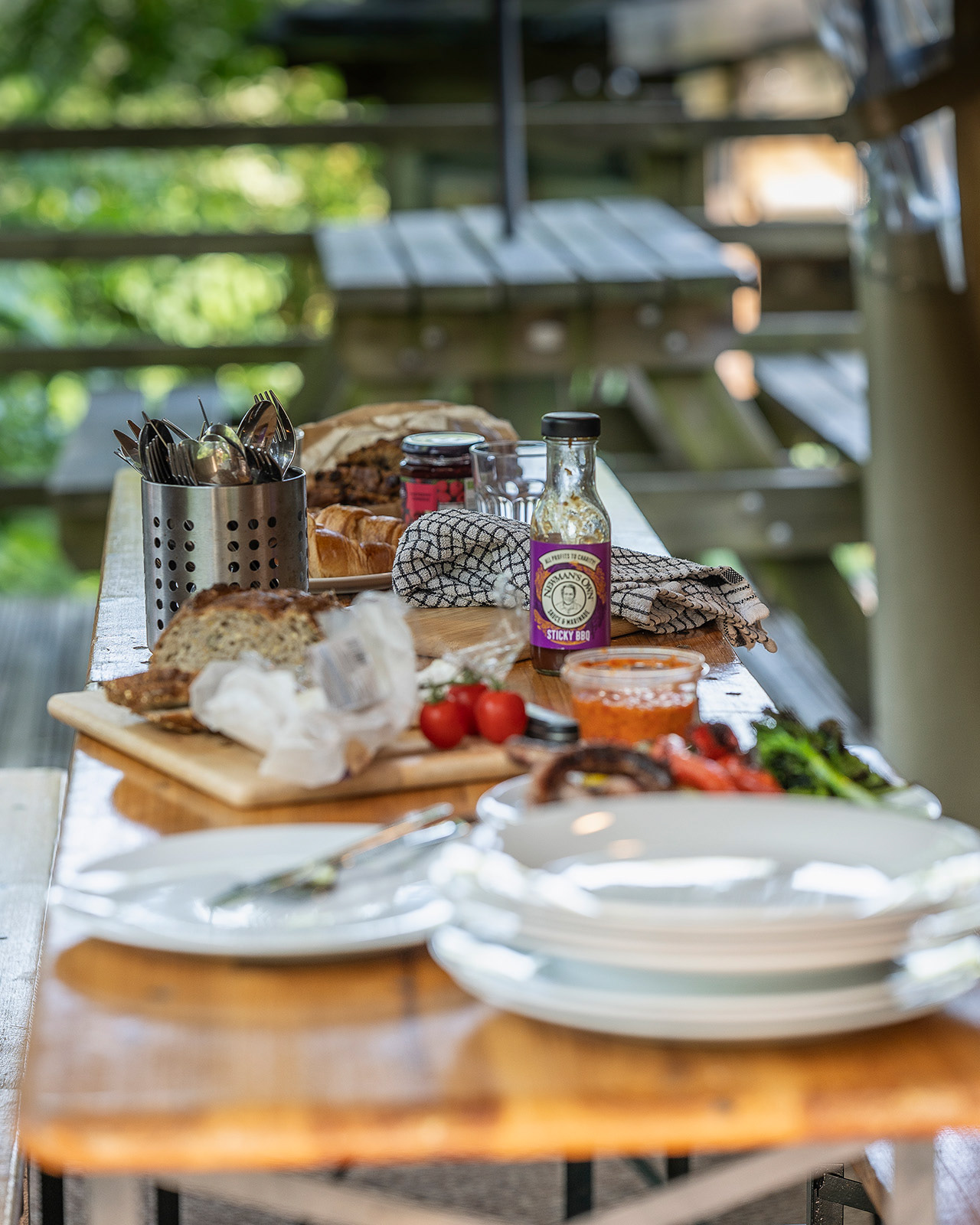 A beautifully set dining table in the shared kitchen at Roost Merthyr Tydfil, with food, plates and utensils ready for a meal. Shot with a shallow depth of field to capture the relaxed, welcoming atmosphere of this South Wales glamping accommodation.