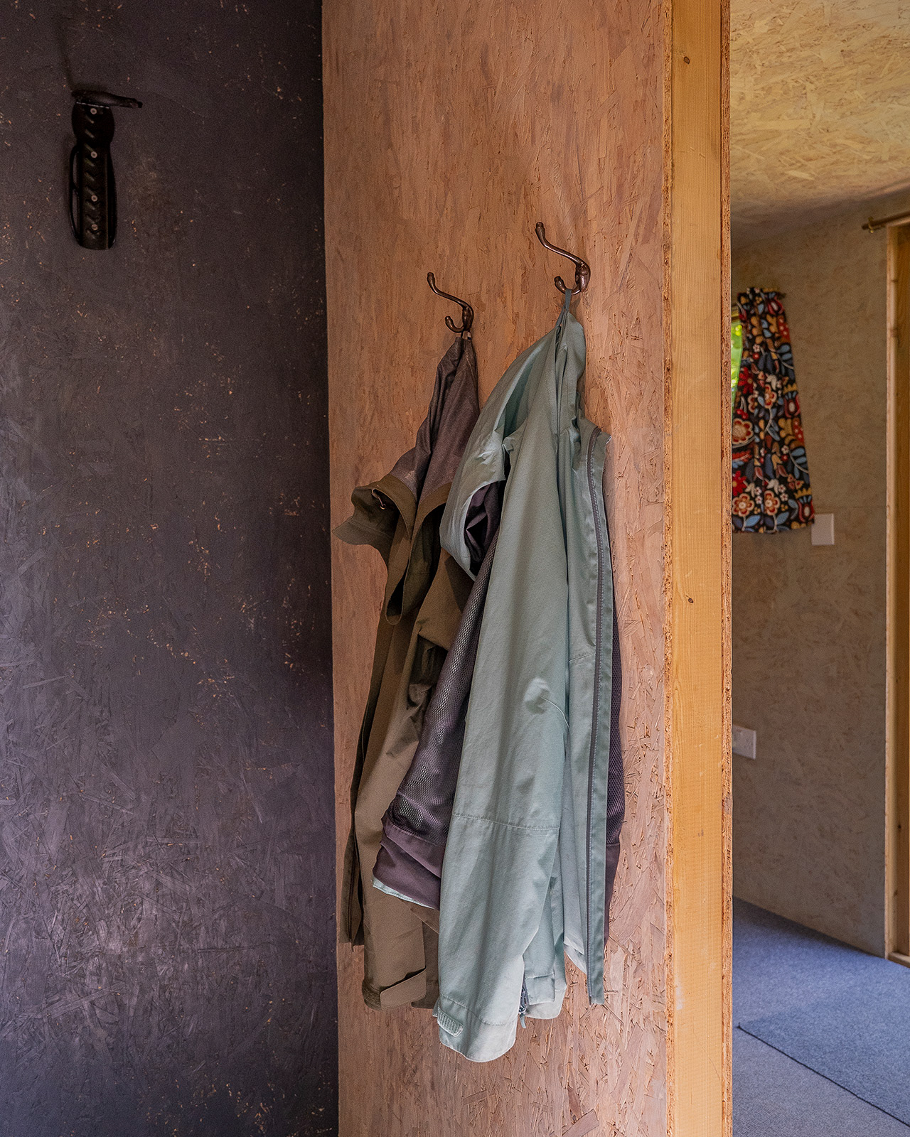 The entrance to Gwynfa cabin at Roost Merthyr Tydfil, with a bike hook, coat hooks and a glimpse into the bedroom area. A practical and welcoming space designed for comfortable glamping stays in South Wales.