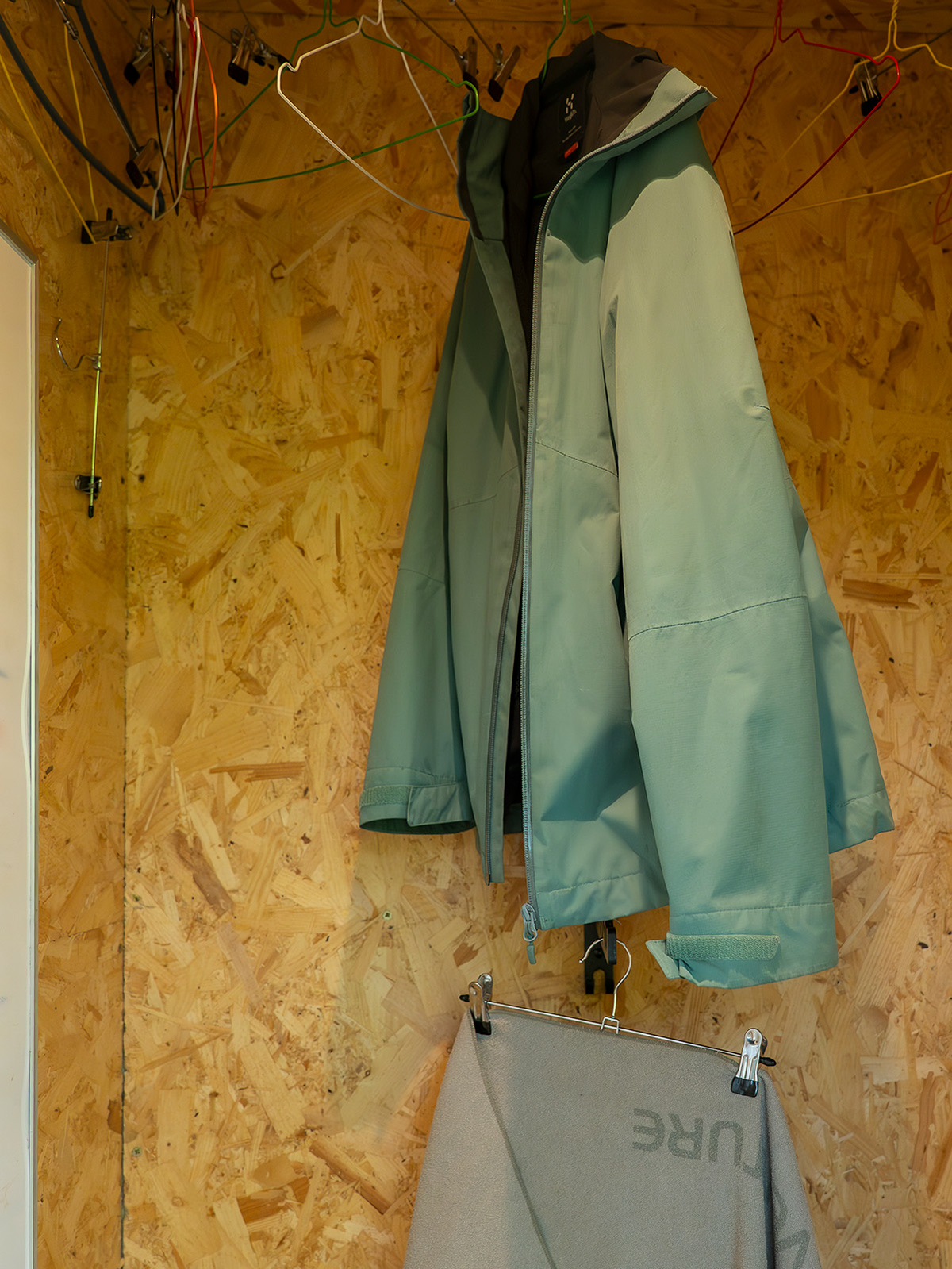 The drying room at Roost Merthyr Tydfil, with a jacket hanging on the hangers and a towel drying beneath, alongside space for guests to hang wet outdoor clothing. A practical facility for exploring the South Wales countryside in all weather.