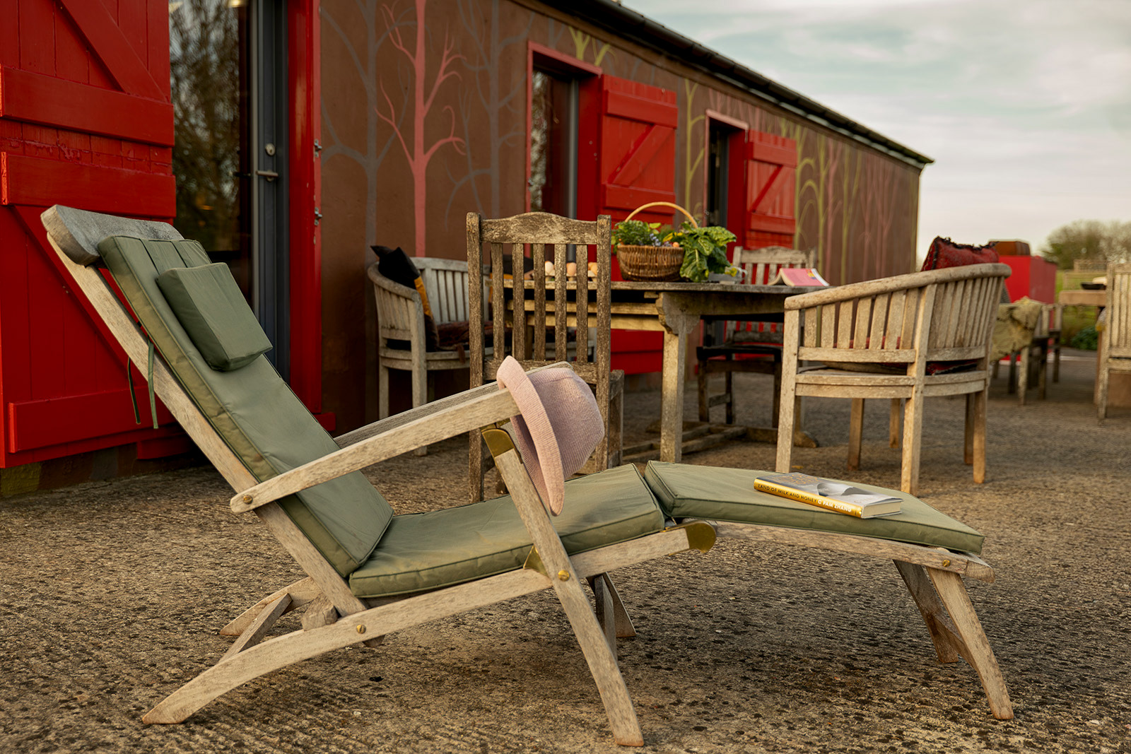 Outdoor hospitality photography at Woodlands Farm Wales, showcasing a garden lounger with a book and the relaxed outdoor seating area on the Pavilion patio.