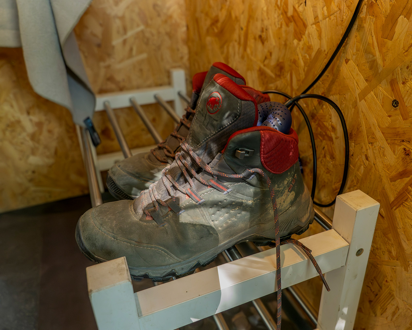 Walking boots on the boot rack at Roost Merthyr Tydfil, with heated boot dryers inside to keep wet footwear warm and dry after exploring the South Wales countryside. A practical facility for guests enjoying an outdoor glamping stay.