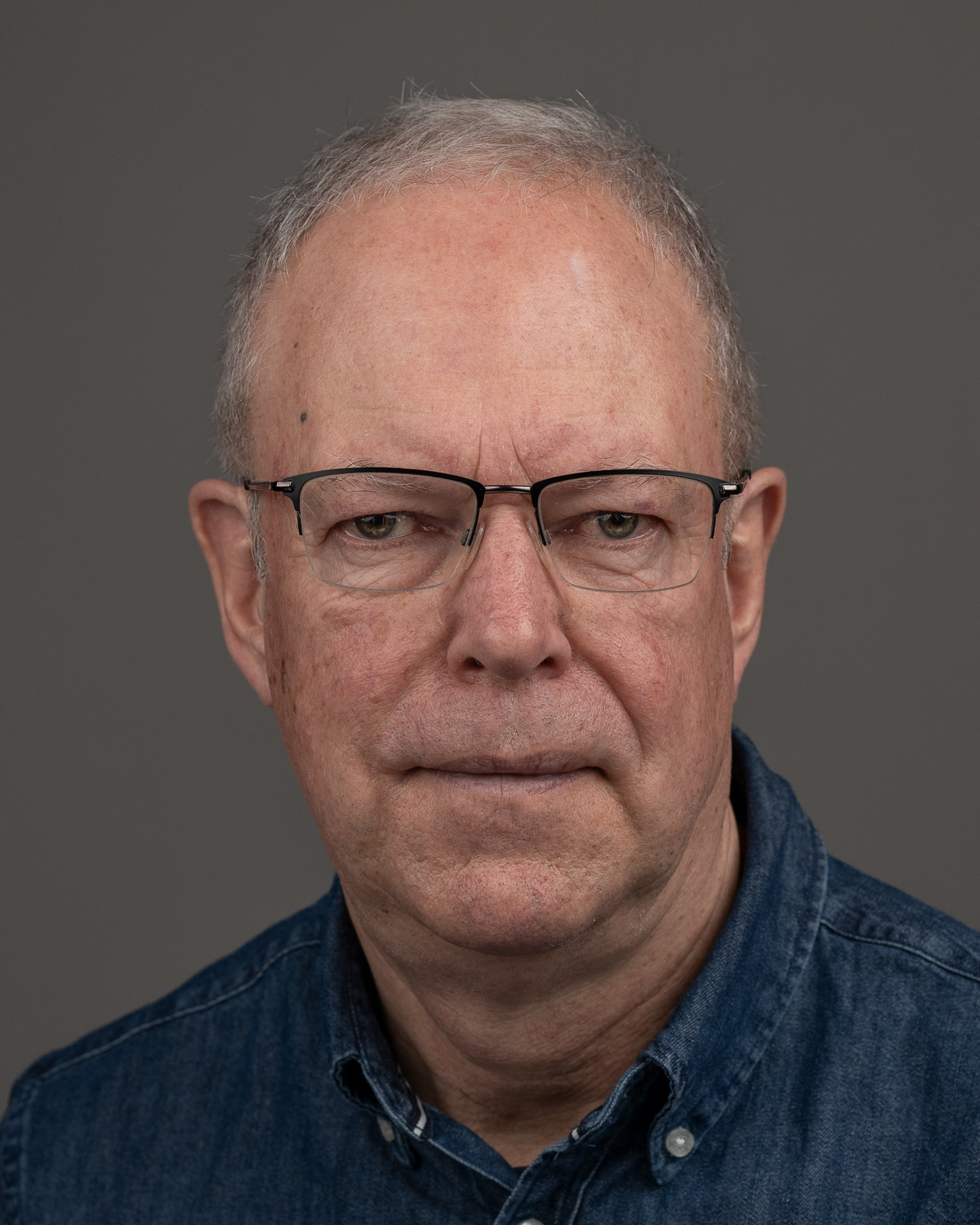 Headshot, front-facing, grey backdrop