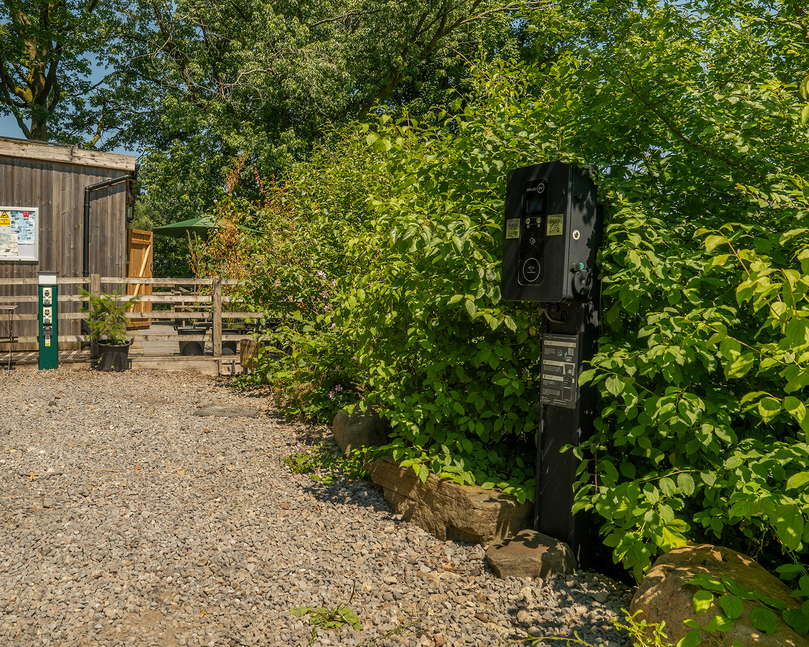 The EV charging point at Roost Merthyr Tydfil, with the guest parking area and shower facilities set among the surrounding greenery. A practical feature for guests arriving at this South Wales glamping accommodation.