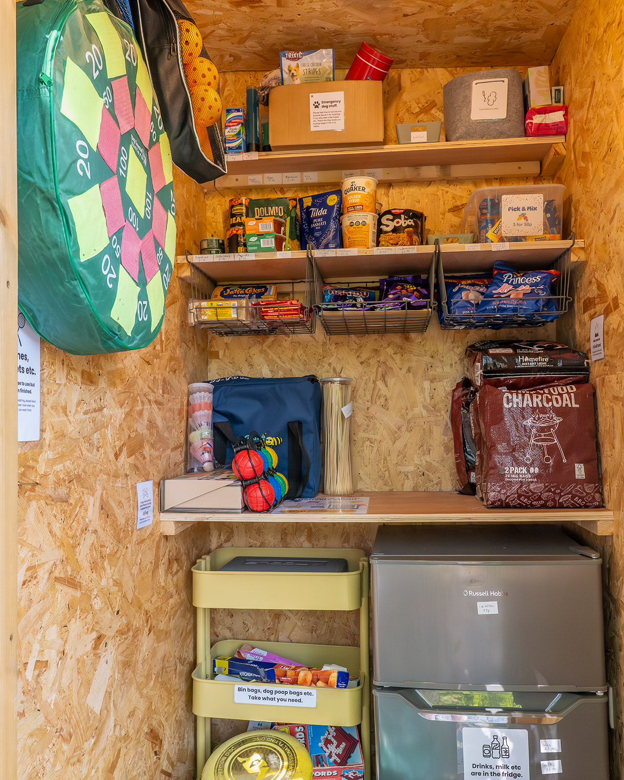 The guest shop at Roost Merthyr Tydfil, with a fridge, charcoal, snacks and food supplies alongside outdoor games equipment. A convenient facility offering useful essentials for guests staying at this South Wales glamping accommodation.