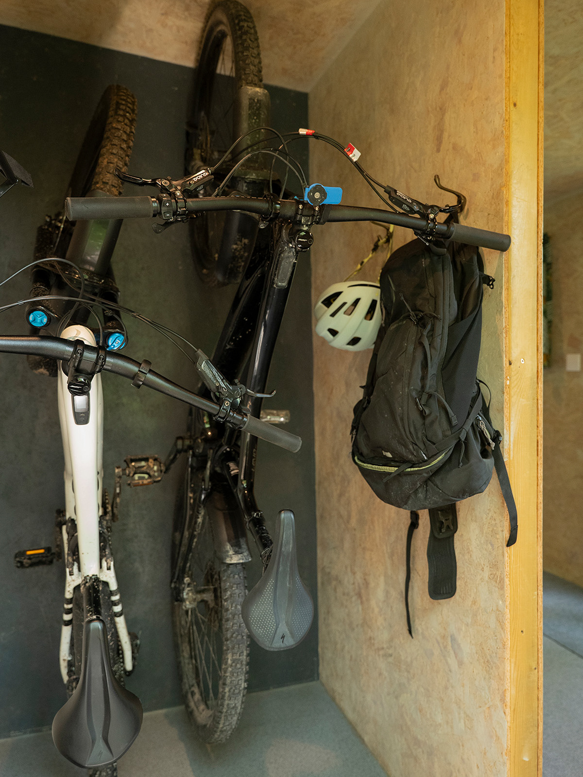 The entrance to Noddfa cabin at Roost Merthyr Tydfil, with two bicycles secured on the indoor bike hooks and a rucksack and helmet hanging from the coat hooks. A practical setup for guests enjoying cycling and outdoor adventures in South Wales.
