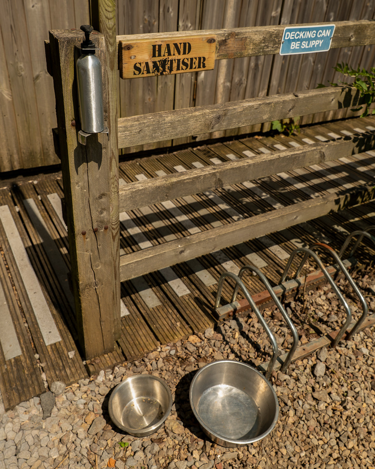 A practical guest facilities detail at Roost Merthyr Tydfil, showing a bicycle stand, dog bowls and a hand sanitiser station, highlighting the thoughtful amenities provided for visitors and their dogs.