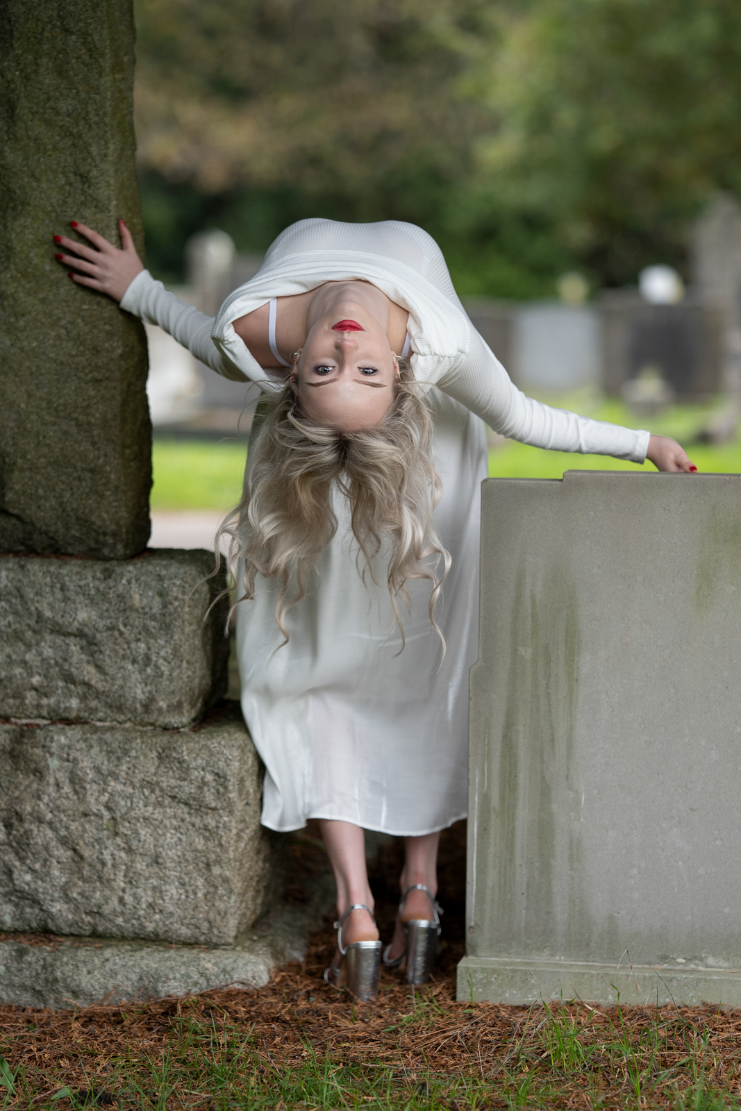 Imogen posing in white dress among gravestones