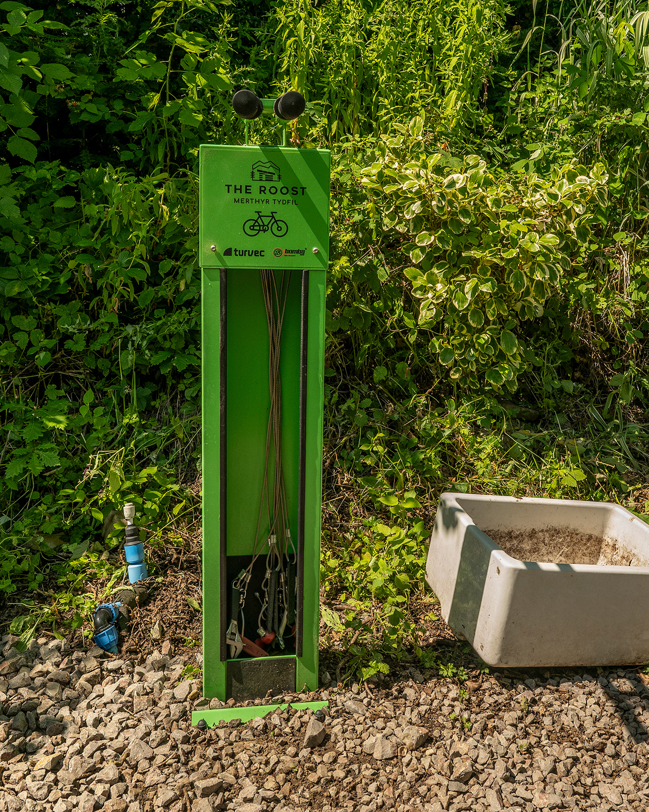 The bike repair station at Roost Merthyr Tydfil, with a traditional white Belfast sink and practical facilities for maintaining bicycles. Surrounded by greenery, it is a useful feature for guests exploring the South Wales countryside by bike.