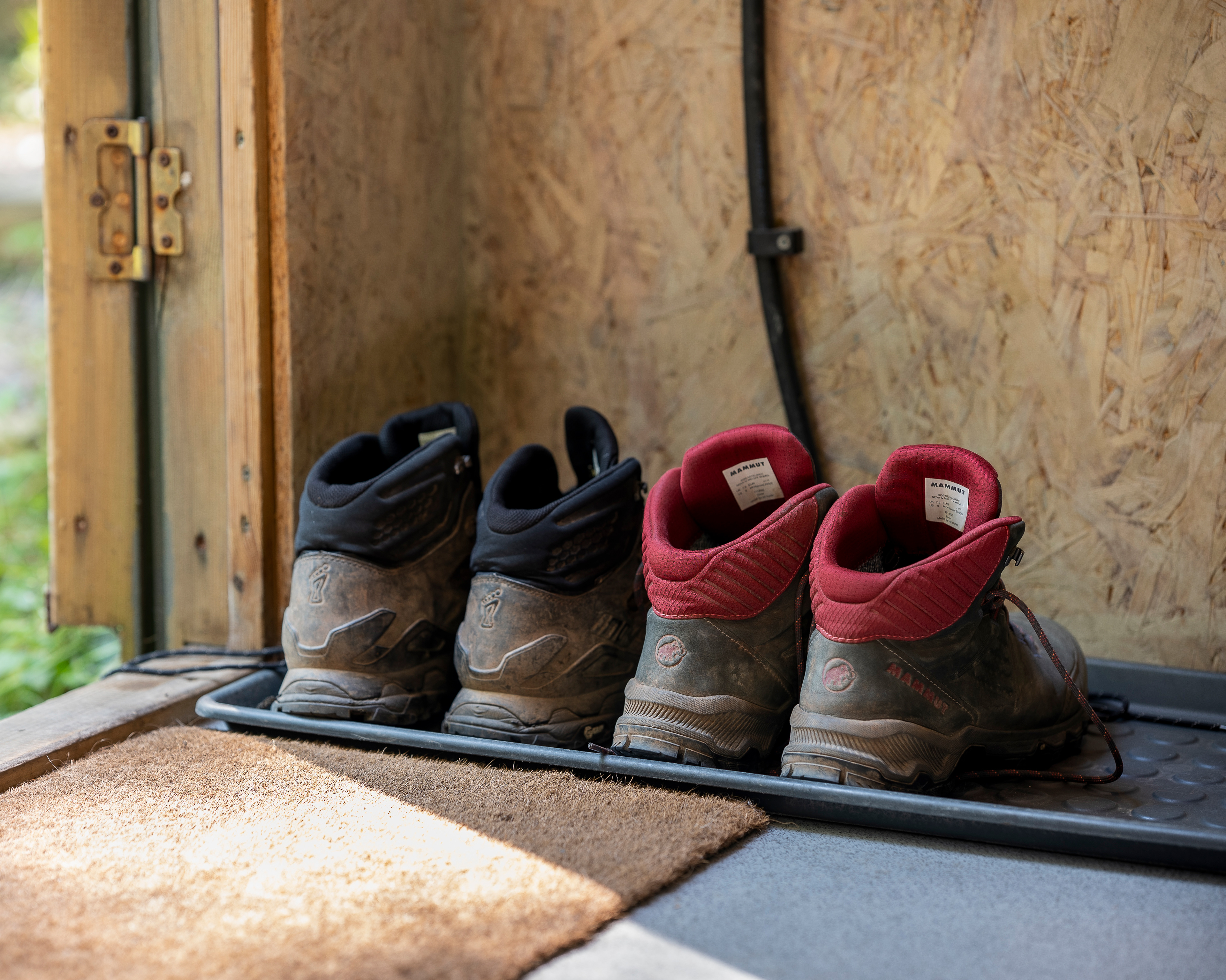 Walking boots ready by the main door of Noddfa cabin at Roost Merthyr Tydfil, highlighting the practical, adventure-friendly setting of this South Wales glamping accommodation.