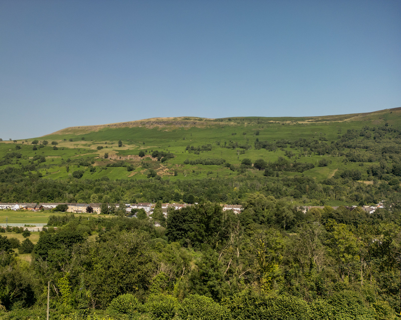 Aerial view of the rolling hills surrounding Roost Merthyr Tydfil, captured by drone and showcasing the green Welsh countryside. A beautiful glimpse of the natural landscape surrounding this South Wales glamping accommodation.