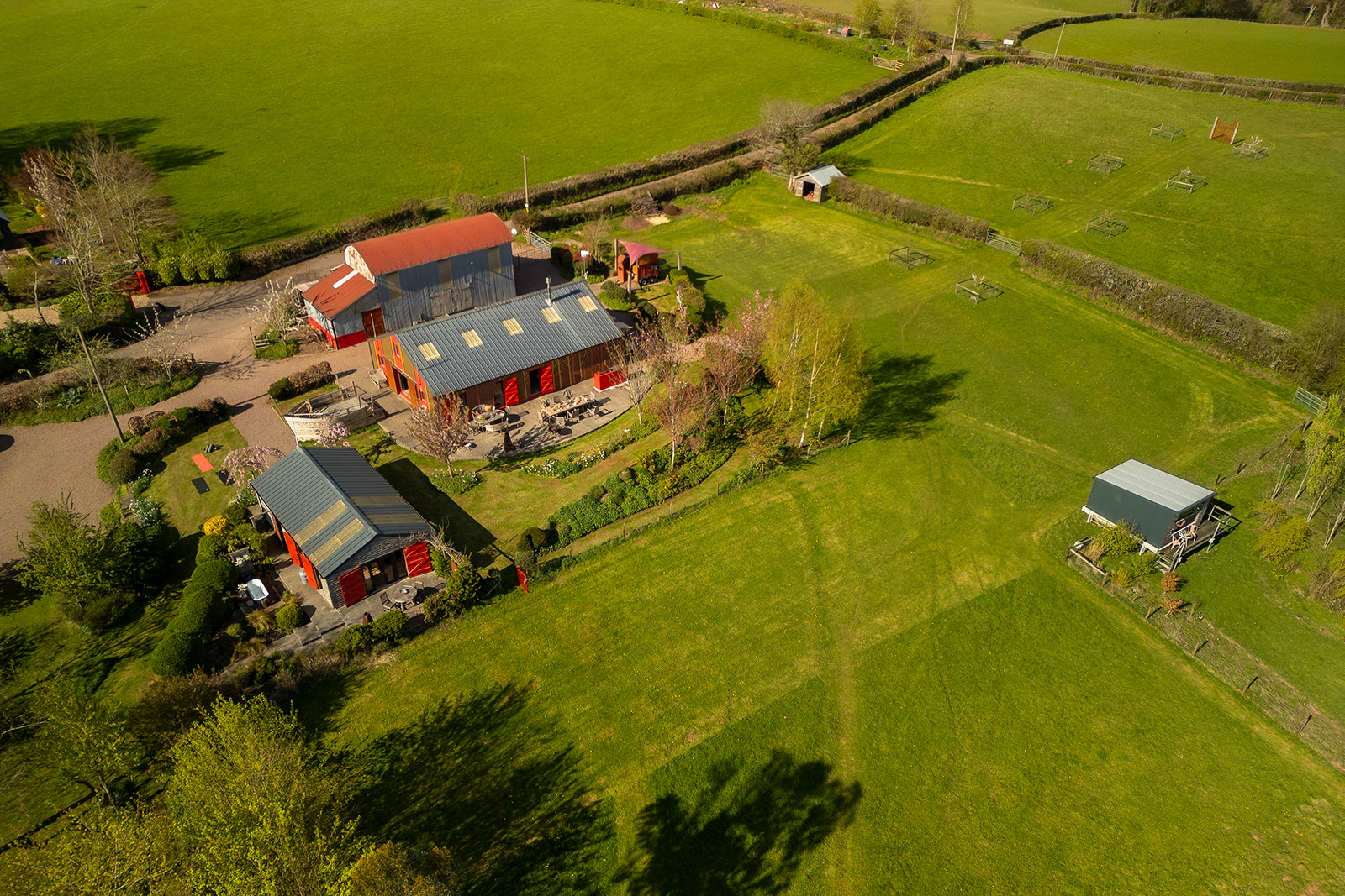 Aerial hospitality photography of Woodlands Farm Wales, showcasing the outdoor spaces and accommodation available for group stays, including The Pavilion and Bivouac.