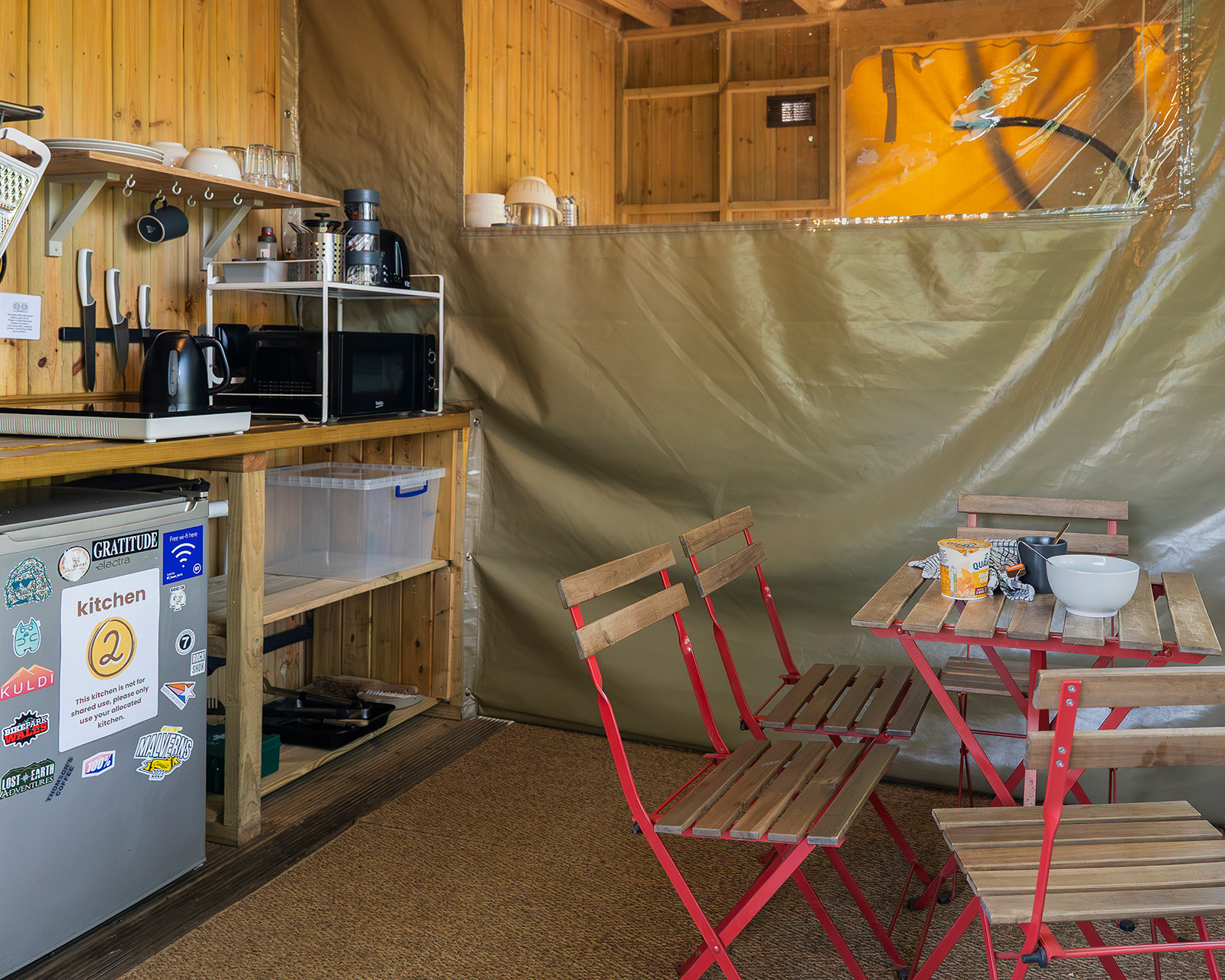 A view of Kitchen 2 at Roost Merthyr Tydfil, with the table and chairs set ready for breakfast. The dividing wall between Kitchen 2 and Kitchen 1 is clearly visible, showing how the two kitchen spaces can be separated or opened up for larger groups.