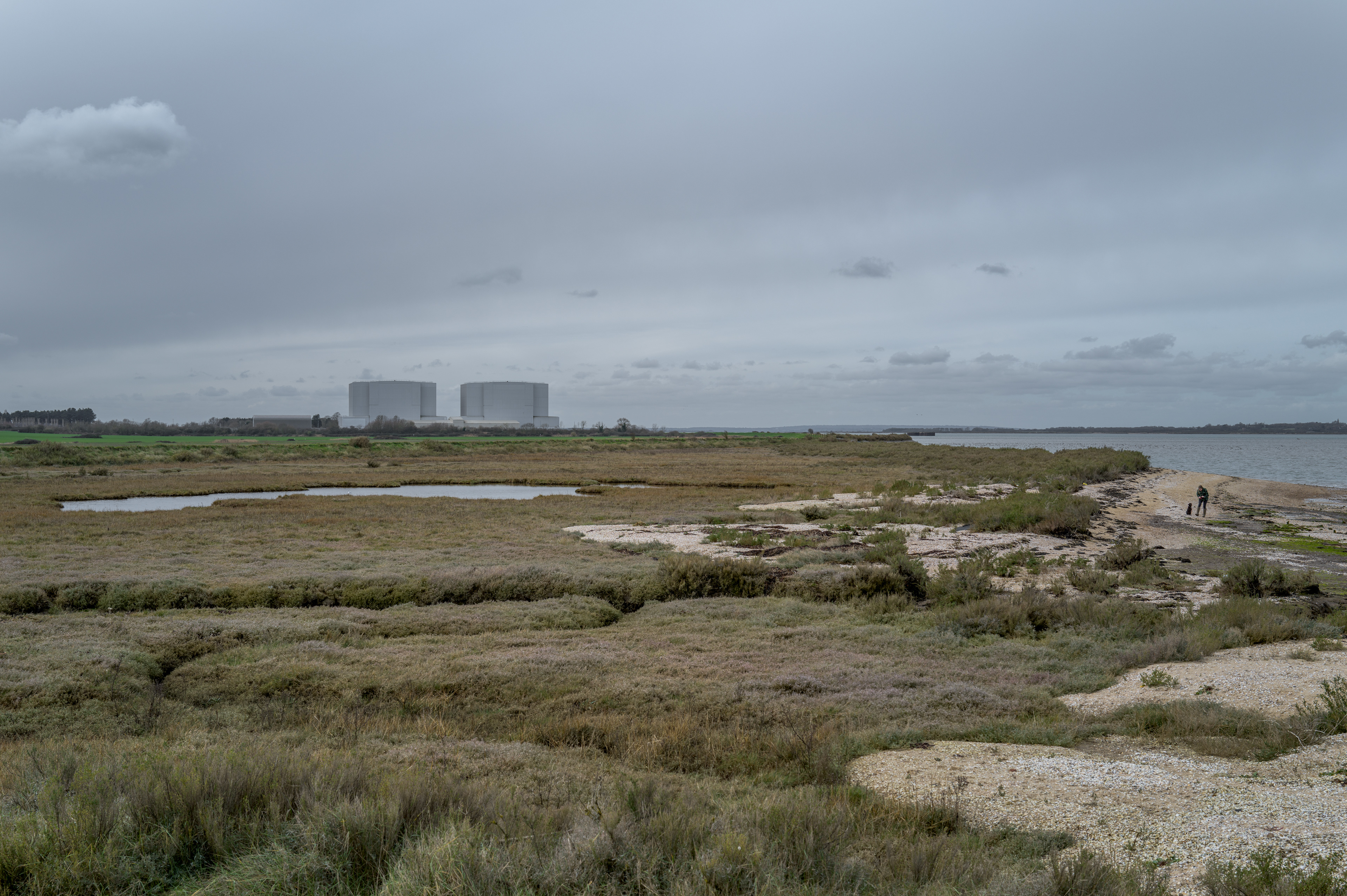 This is an image of the former Bradwell Power Station on the Dengie Peninsula in Essex seen across the salt marshes in its Care and maintenance Phase following Decommissioning. The original building was by the architect Maurice Bebb, with the Safe Store Cladding by ARUP. The site is a former MAGNOX Nuclear Power Station, and the surrounding landscapes were by Dame Sylvia Crowe.