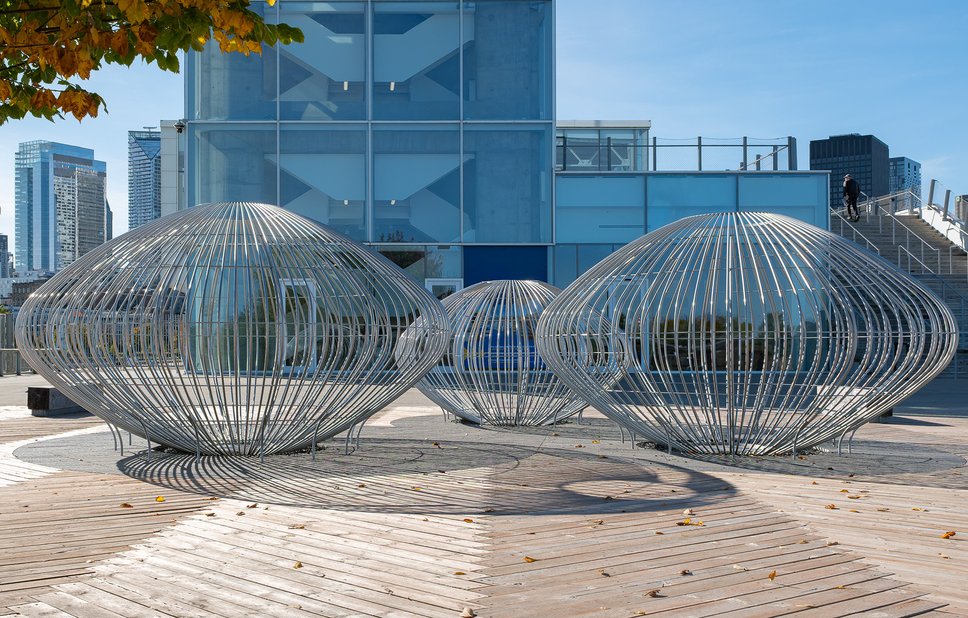 Gros plan sur l’œuvre d’art public en acier « Hydrosphères » de Linda Covit sur l'esplanade du Grand Quai de Montréal, conçue par NIPPAYSAGE et Provencher_Roy. La sculpture repose sur un grand platelage en bois au cœur de cet aménagement paysager..