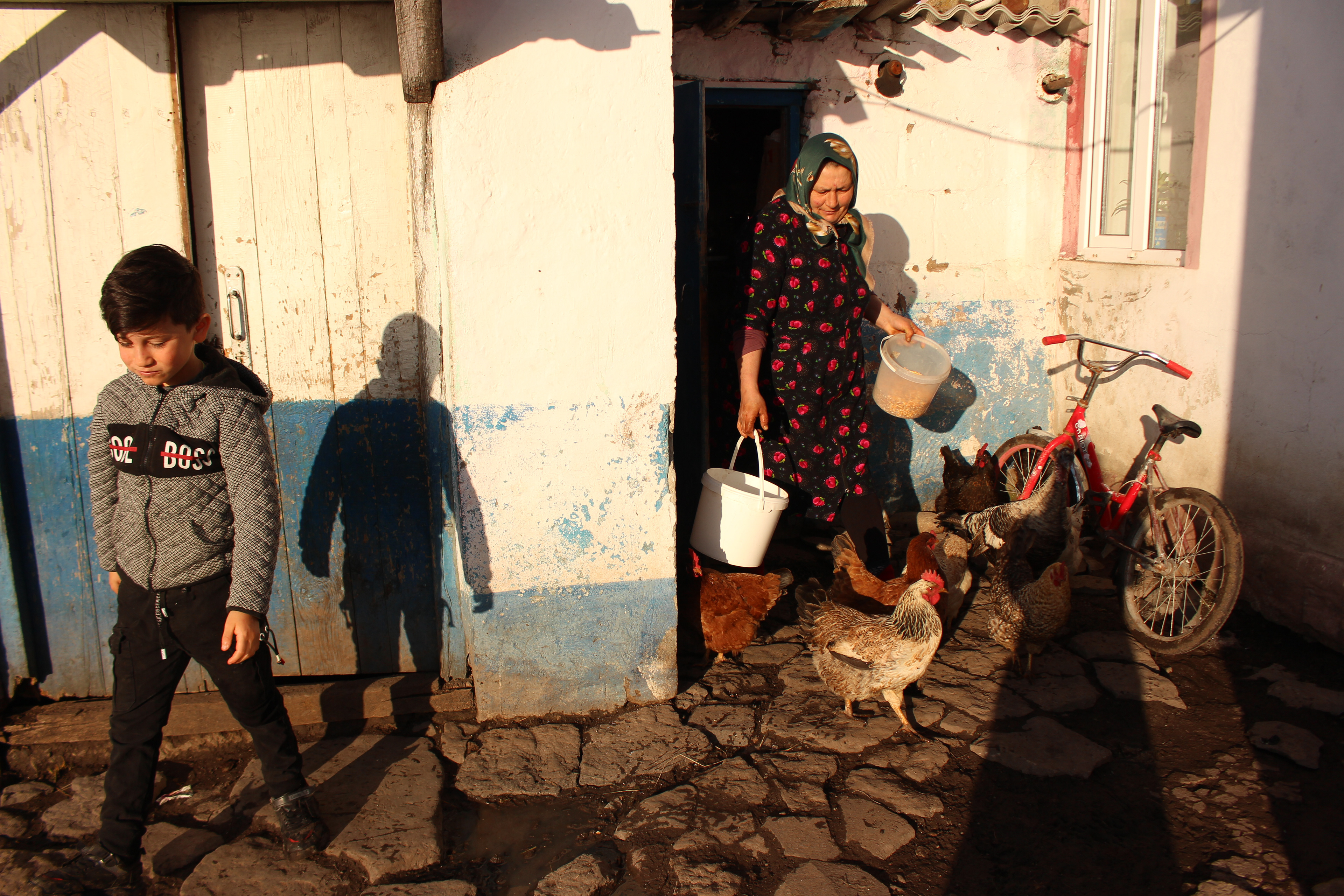 Yetar and Murad, one of her three grandchildren, go through their morning routines. She prepares to feed the chickens while the children get ready for school.
