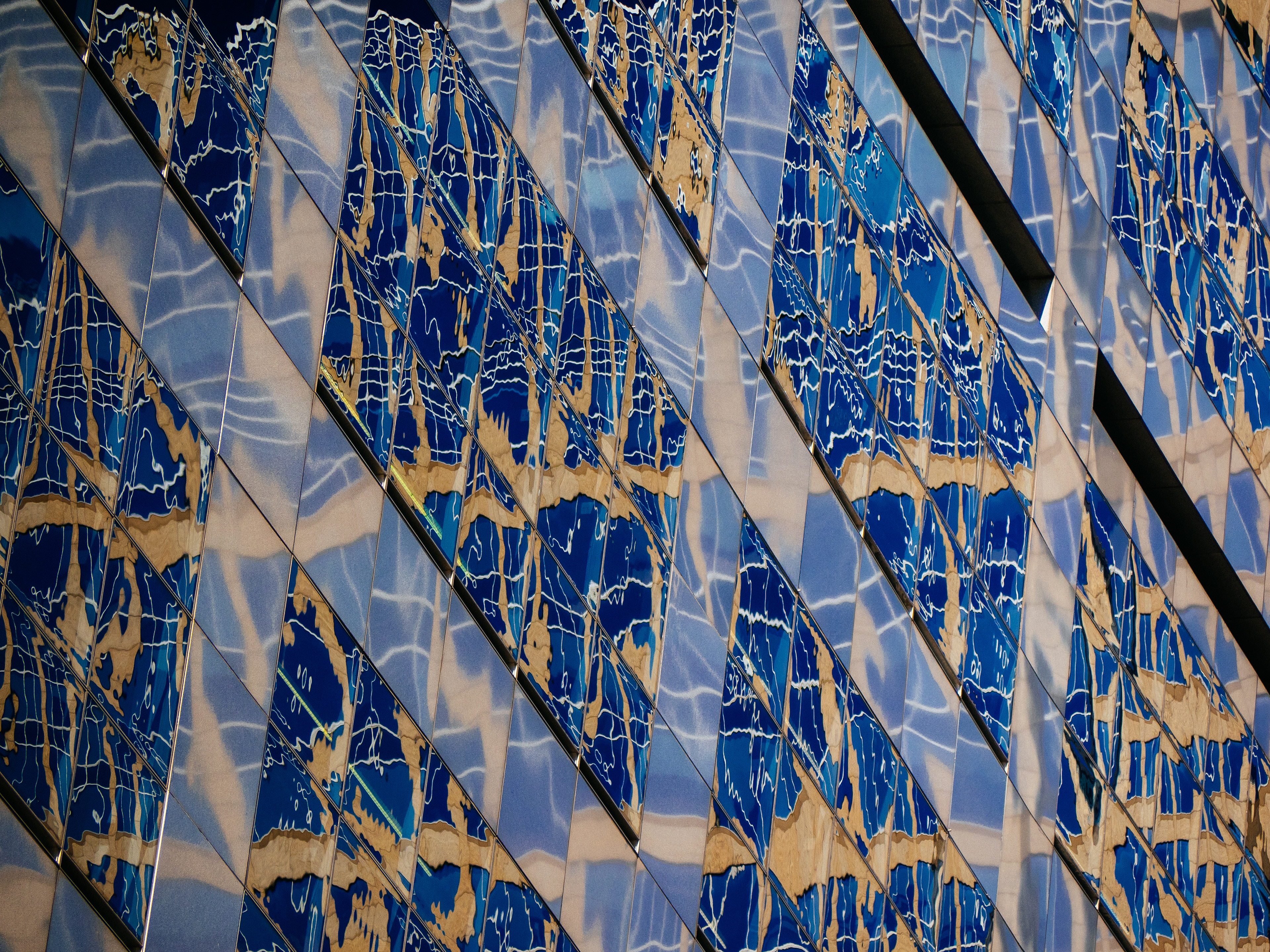 The reflections from the sky and several nearby buildings create an interesting mixture of color and shapes in the windows of building in Houston, Texas, USA.