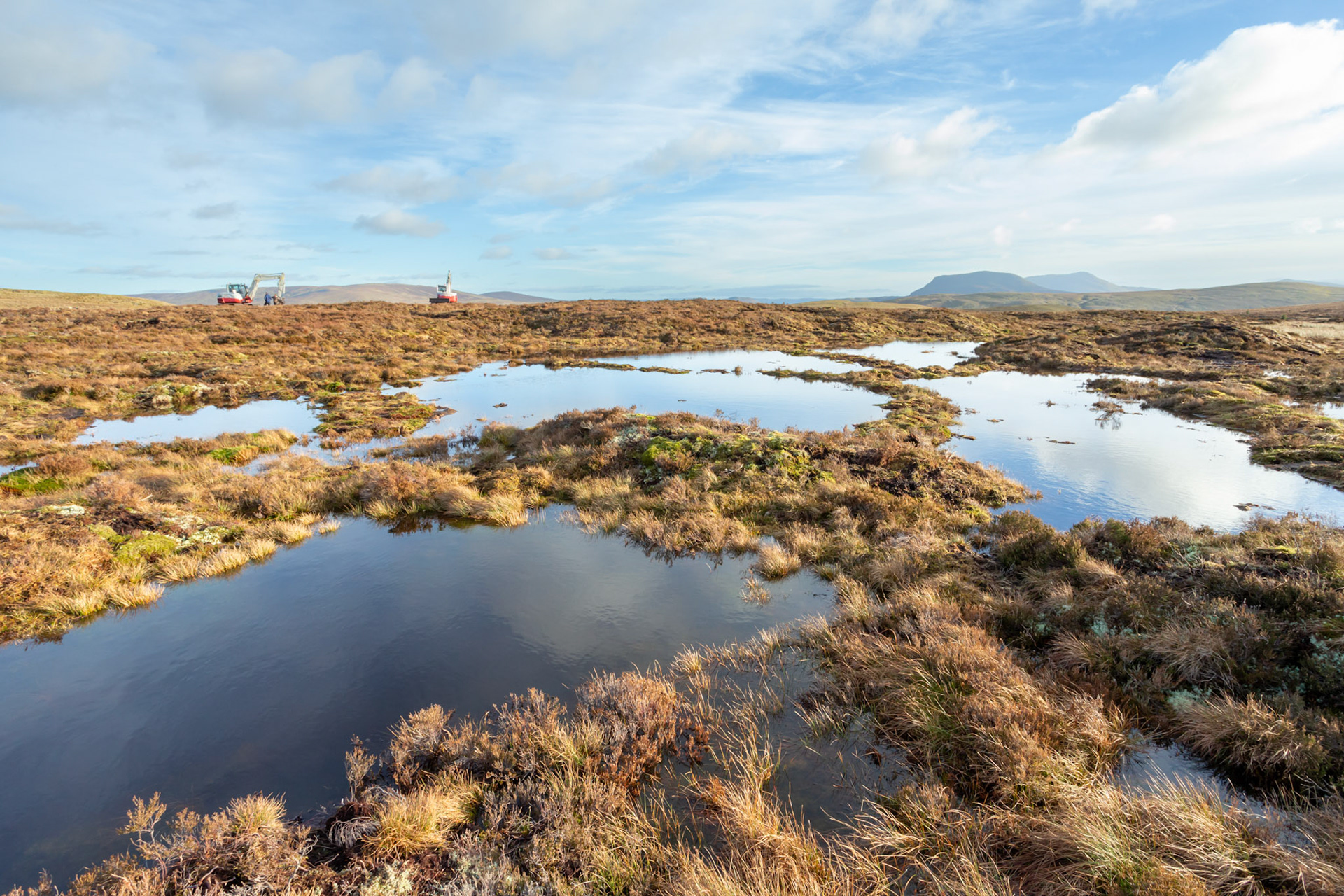 Peatland restoration pools with diggers in the background. Winter, Migneint moors, North Wales, UK