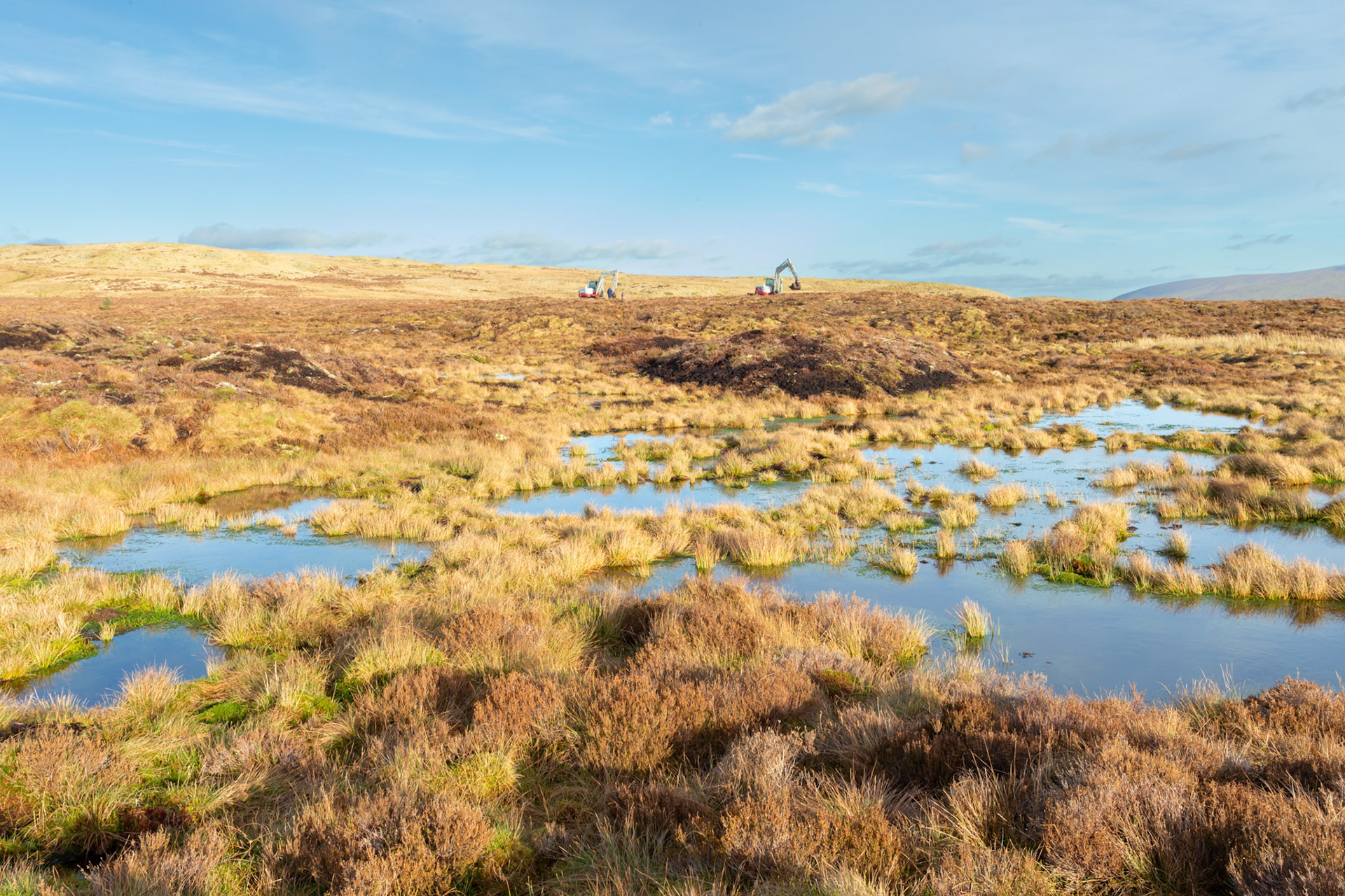 Peatland restoration pools with diggers in the background. Winter, Migneint moors, North Wales, UK