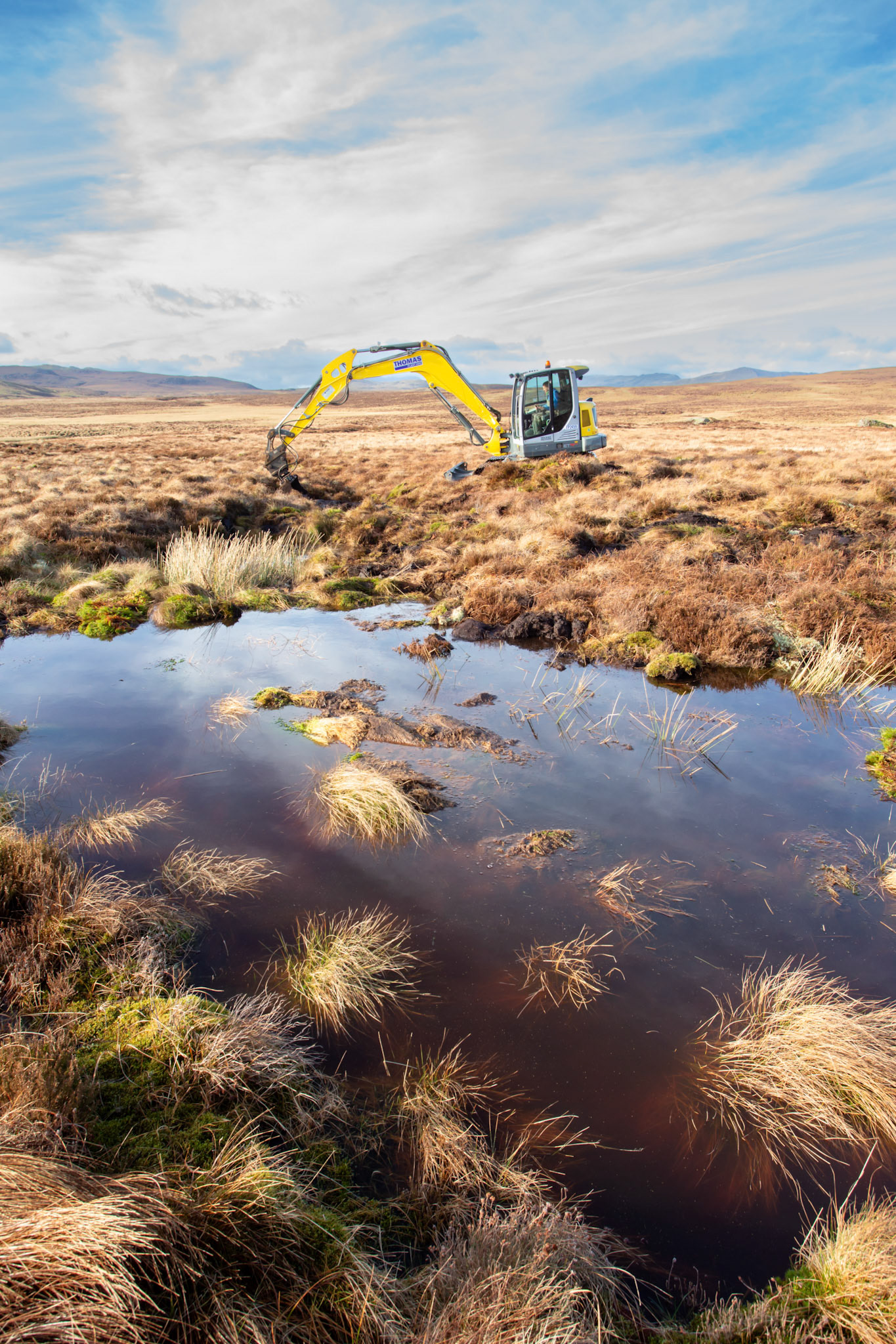 Contractor using digger to carry out peatland restoration work for RSPB peatland restoration project. Winter, Migneint moors, North Wales,UK.