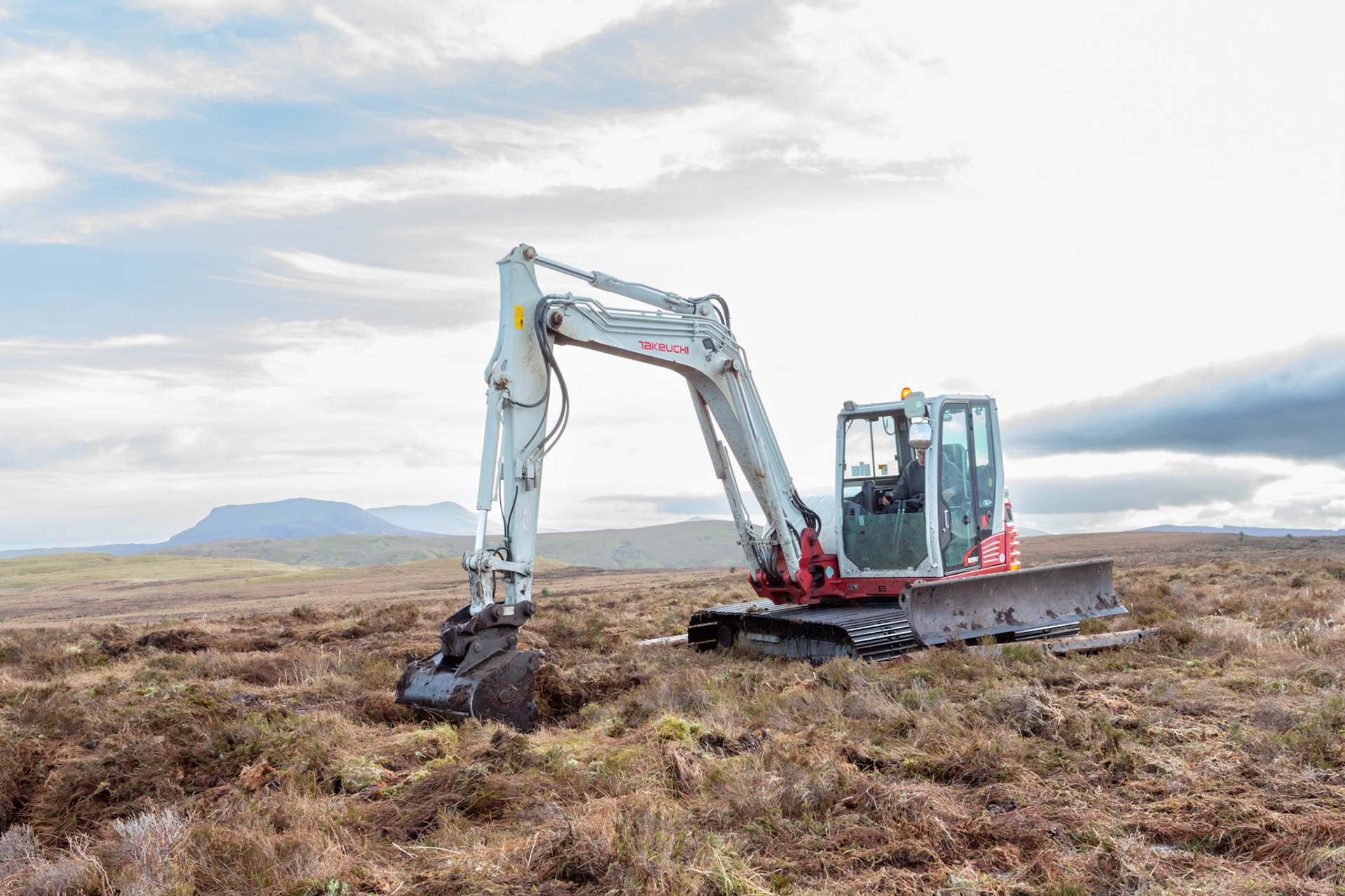 Contractor using digger to carry out peatland restoration work for RSPB peatland restoration project in the wider landscape. Winter, Migneint moors, North Wales,UK