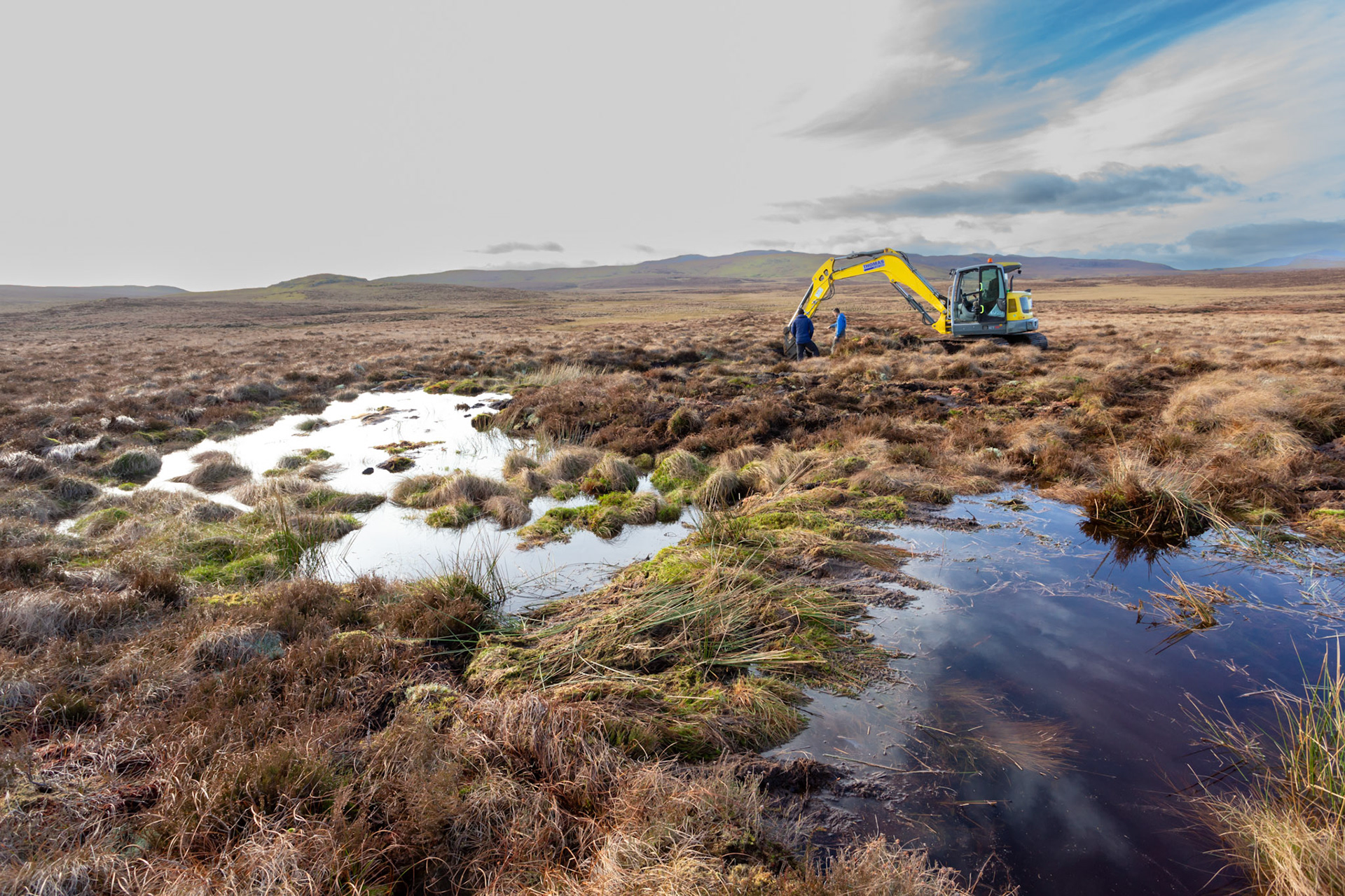 Contractor using digger to carry out peatland restoration work for RSPB peatland restoration project. Winter, Migneint moors, North Wales,UK.