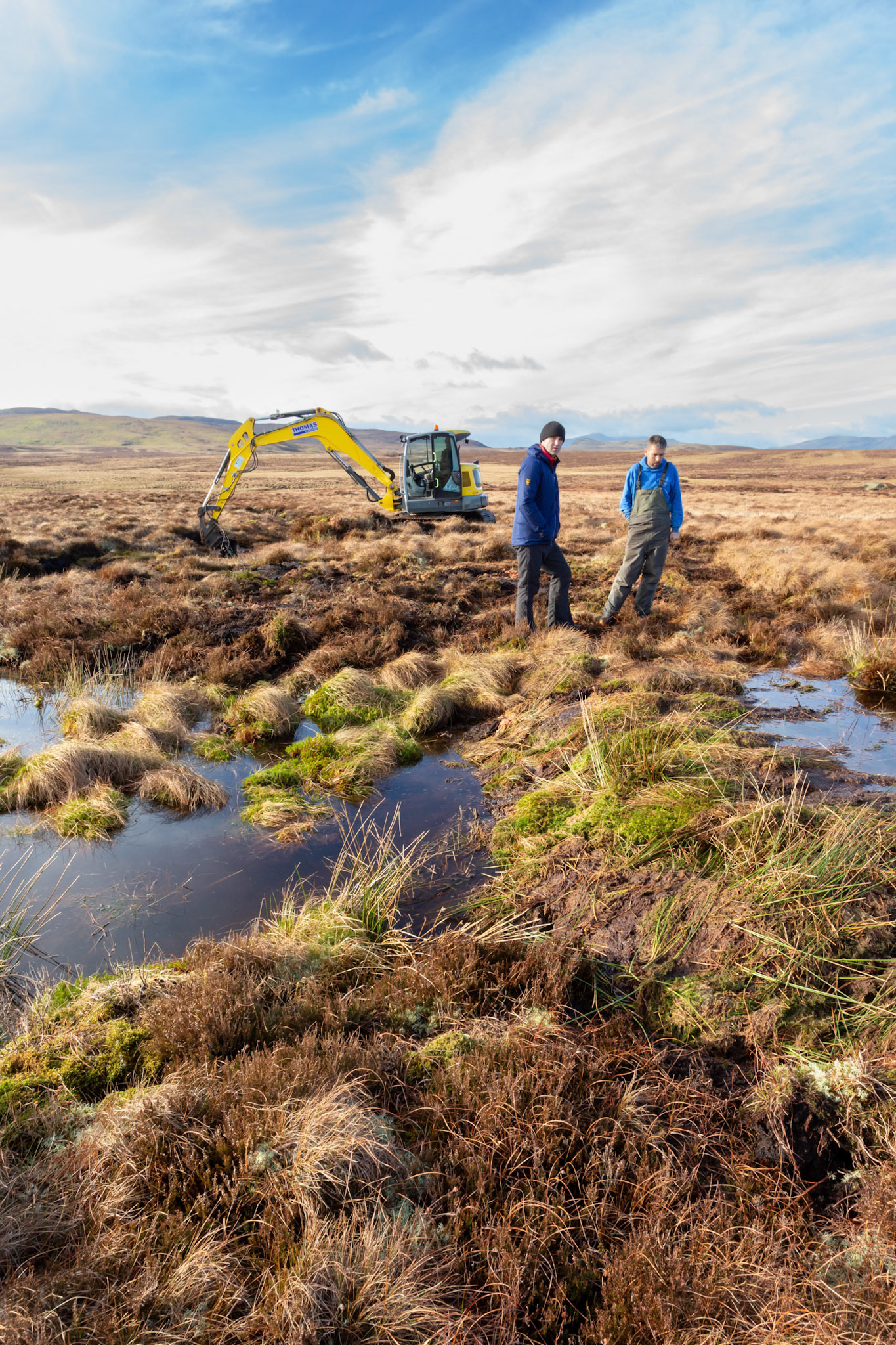 Consevation officer &amp; contractor viewing created dam and pool  on Migneint moors, Winter, North Wales, UK (portrait orientation).