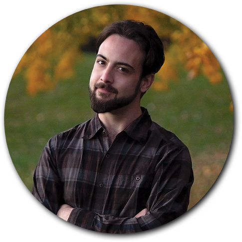 David Vasic, a graphic designer with short brown hair and a warm smile, wearing a button-up shirt against a scenic outdoor fall background with autumn leaves.