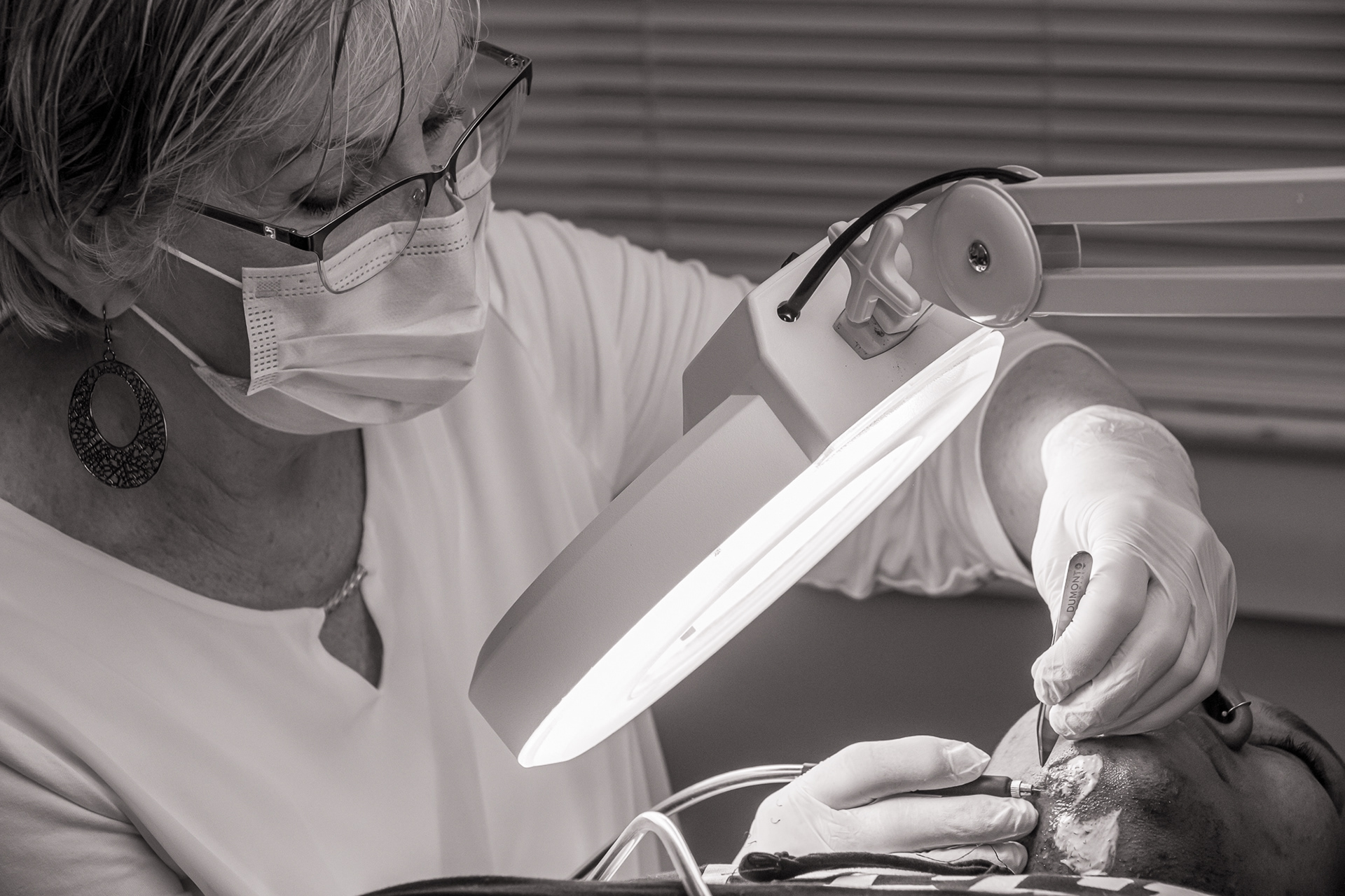 A woman is performing electrolysis on another person.