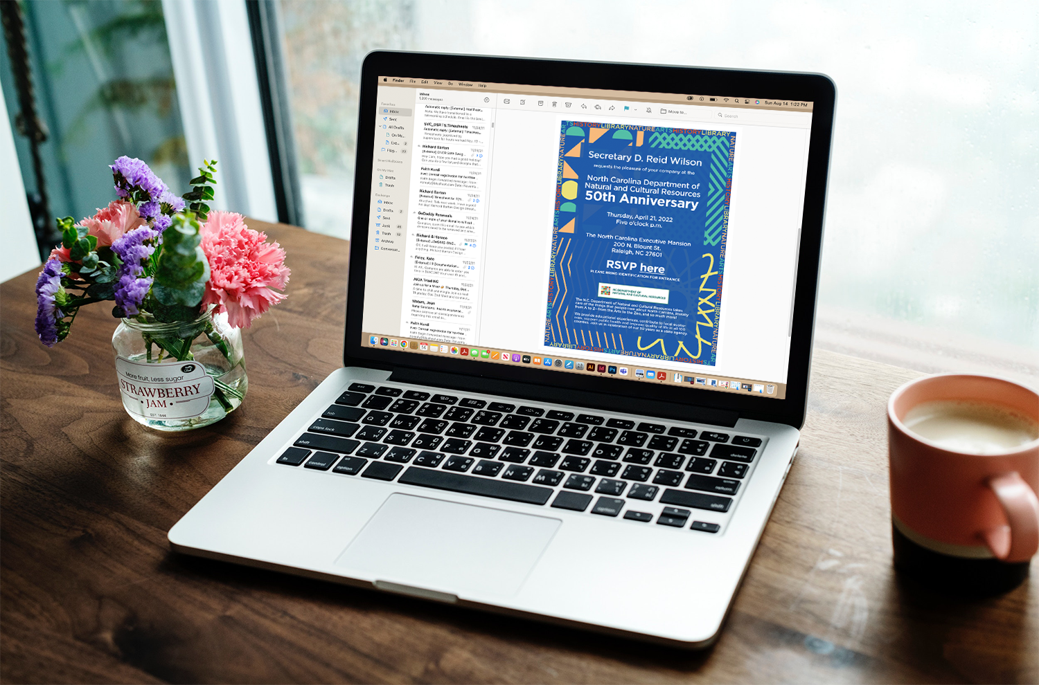 A laptop on a desk with an email showing evite for 50th anniversary event.