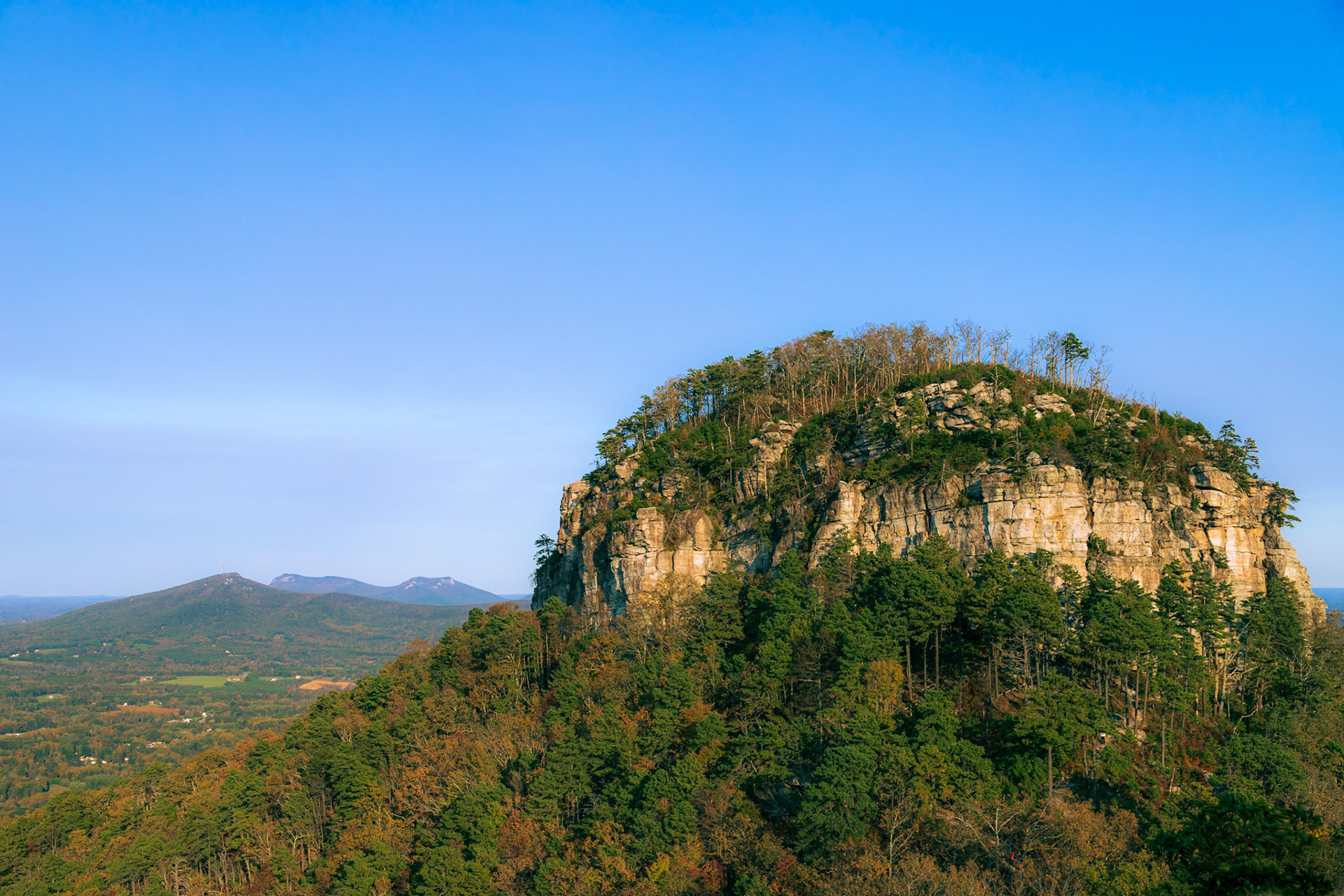 Pilot Mountain in the foreground with several other mountains behind it in the distance.