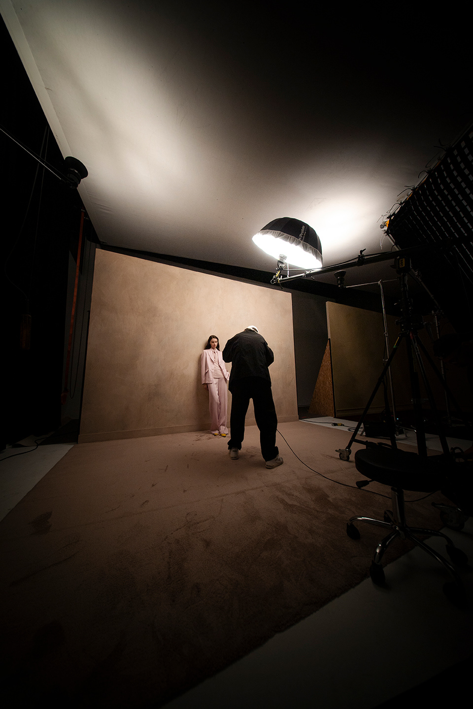 Hinter den Kulissen der LUISA CERANO SS2026: Fotograf passt Pose des Models in hellem Anzug vor beiger Wand im Mode-Studio an