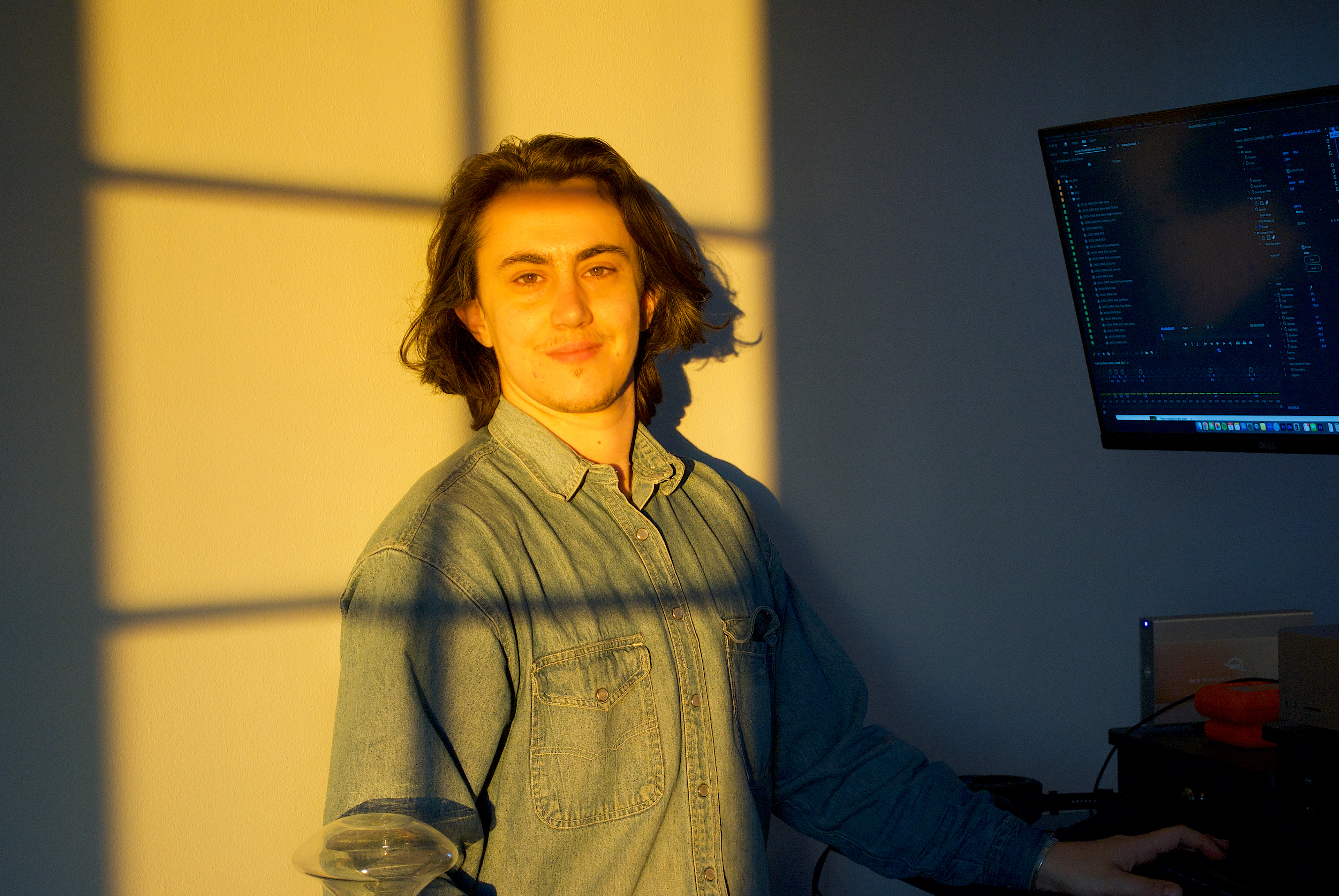 Photo of Miles Hill standing in front of his home editing suite. The sun is warming his face and soul.