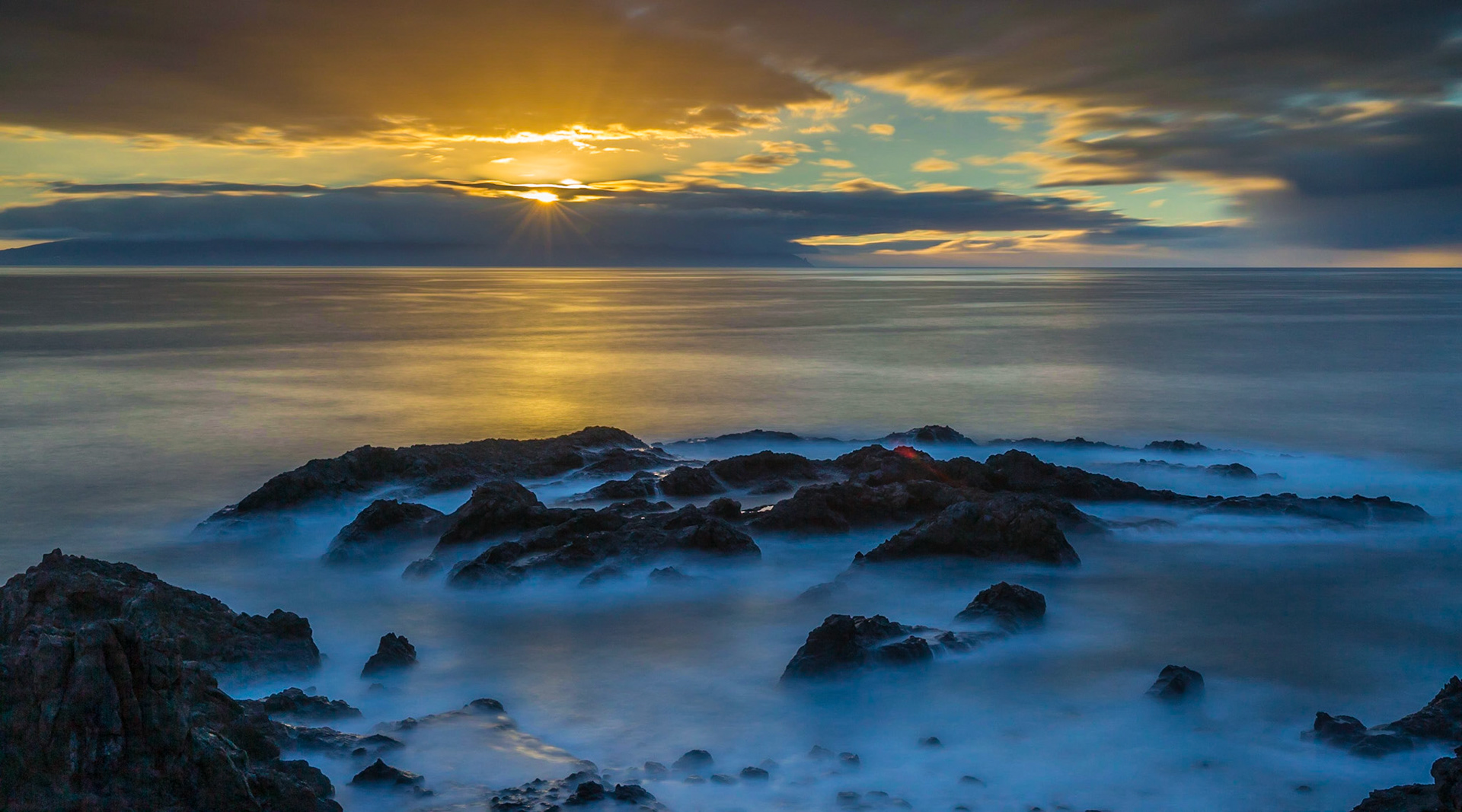 Long exposure of the sunset and ocean coming up on the rock at Los Gigantes in Tenerife