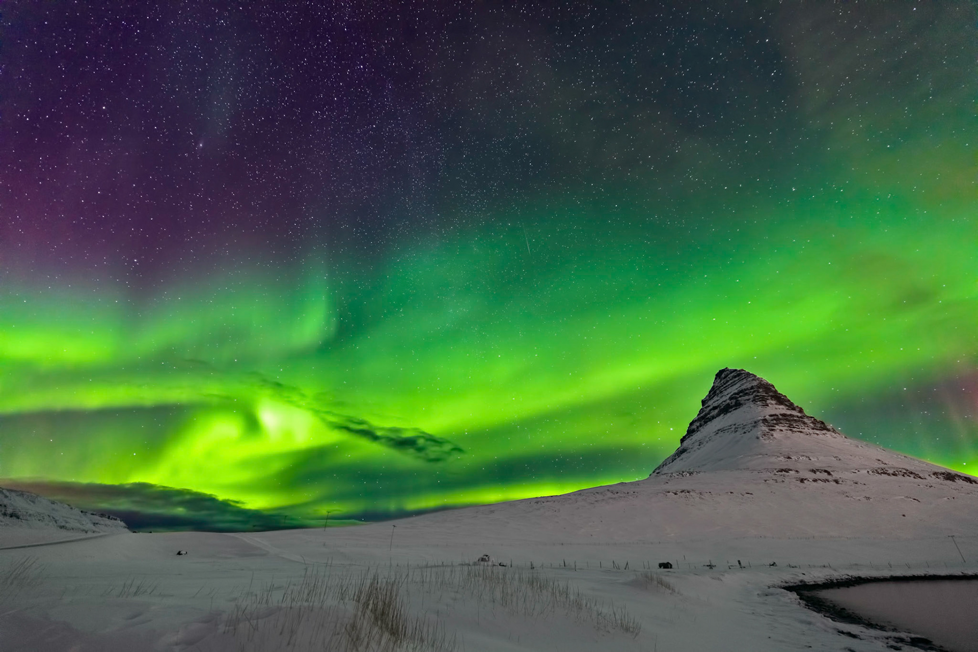 The Aurora Borealis ddancing over the Kirkjufell mountain in Iceland