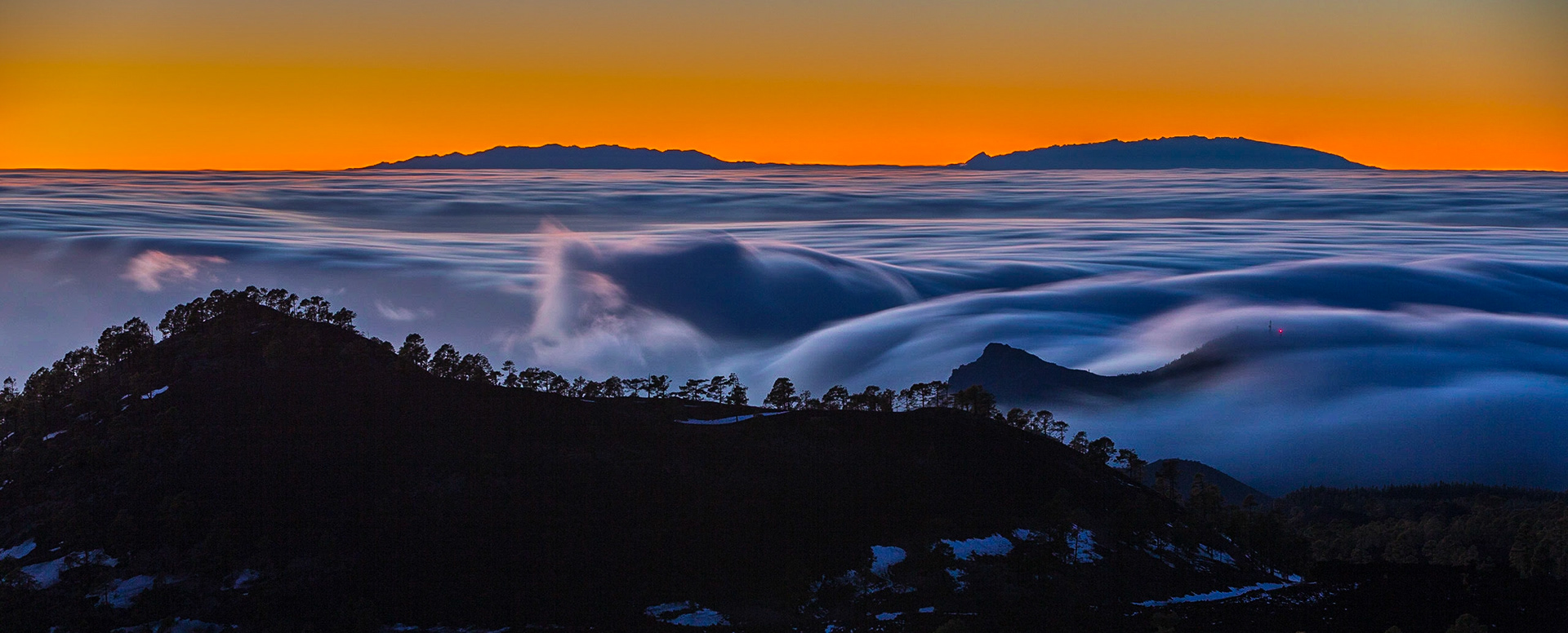 This picture was taken at sunset from the Corona Forestal of El Teide, Tenerife, with the mountain tops peaking through the clouds in the horizon.