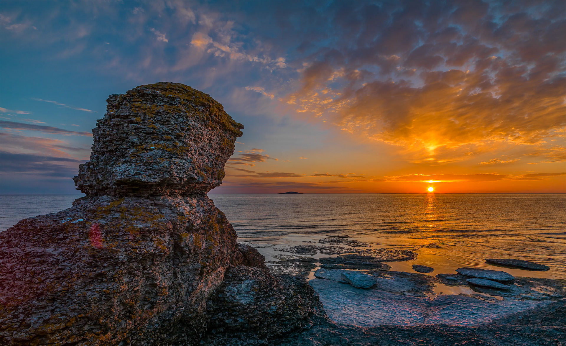 On this beautiful evening the sun sets over sweden casting it's last rays ont the Rauker at Byrum, in center you have the Blaa Jungfruen National Park, swedens smallest.