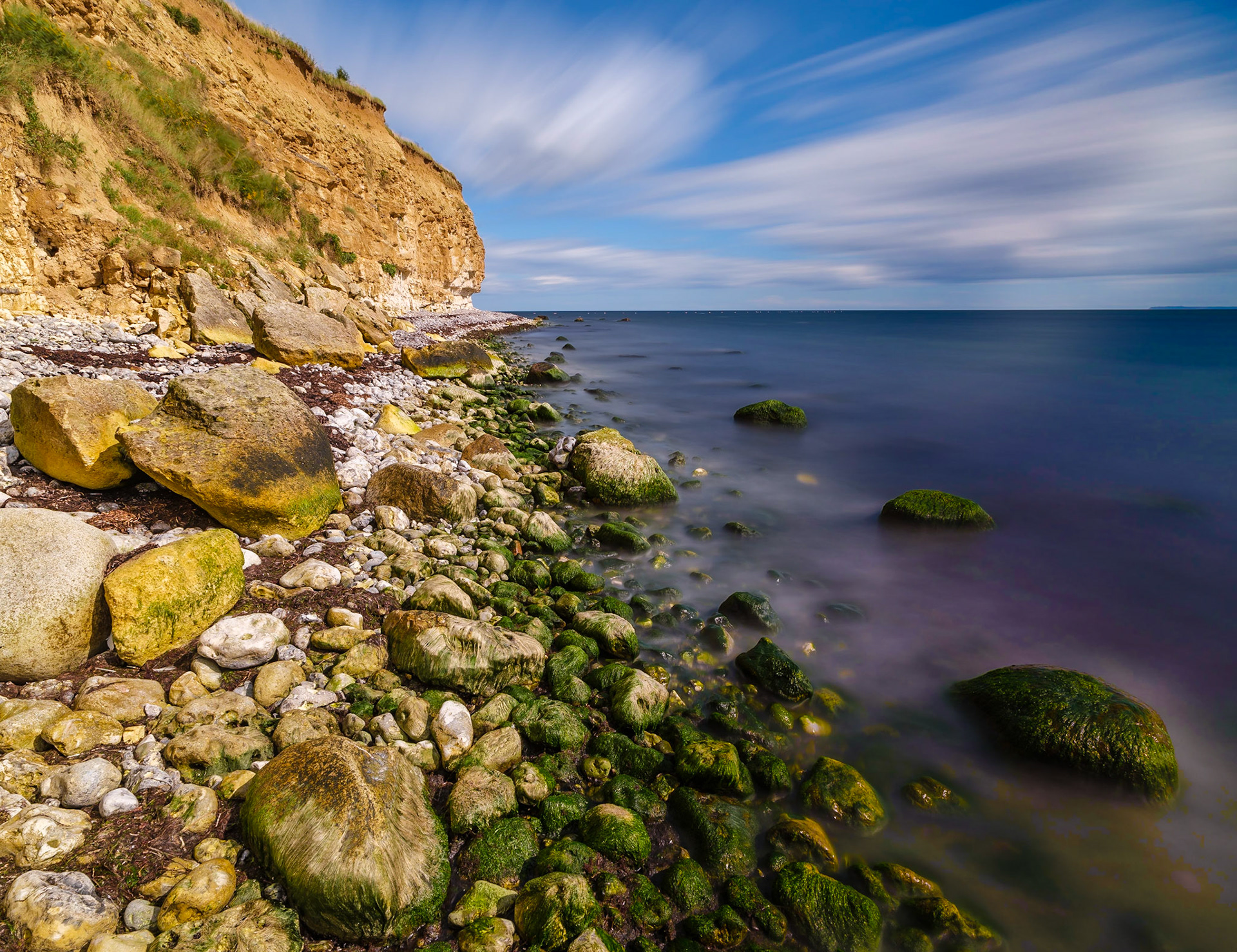 Stevns Klint by Rødvig, Denmark. Beautiful clouds and ocean enhances the stones and cliffs.Exif: Fuji GFX 50S with H-adapter and Hasselblad HCD 24mm, shot at F16 Iso 100 for 4 minutes. NiSi 10 stop ND to reduce the light and prolong the exposure for movement in Clouds and calming of the sea. Gitzo Tripod Series 3 and RRS to hold the rig steady in the wind. iPhone 6+ for entertainment during the exposure