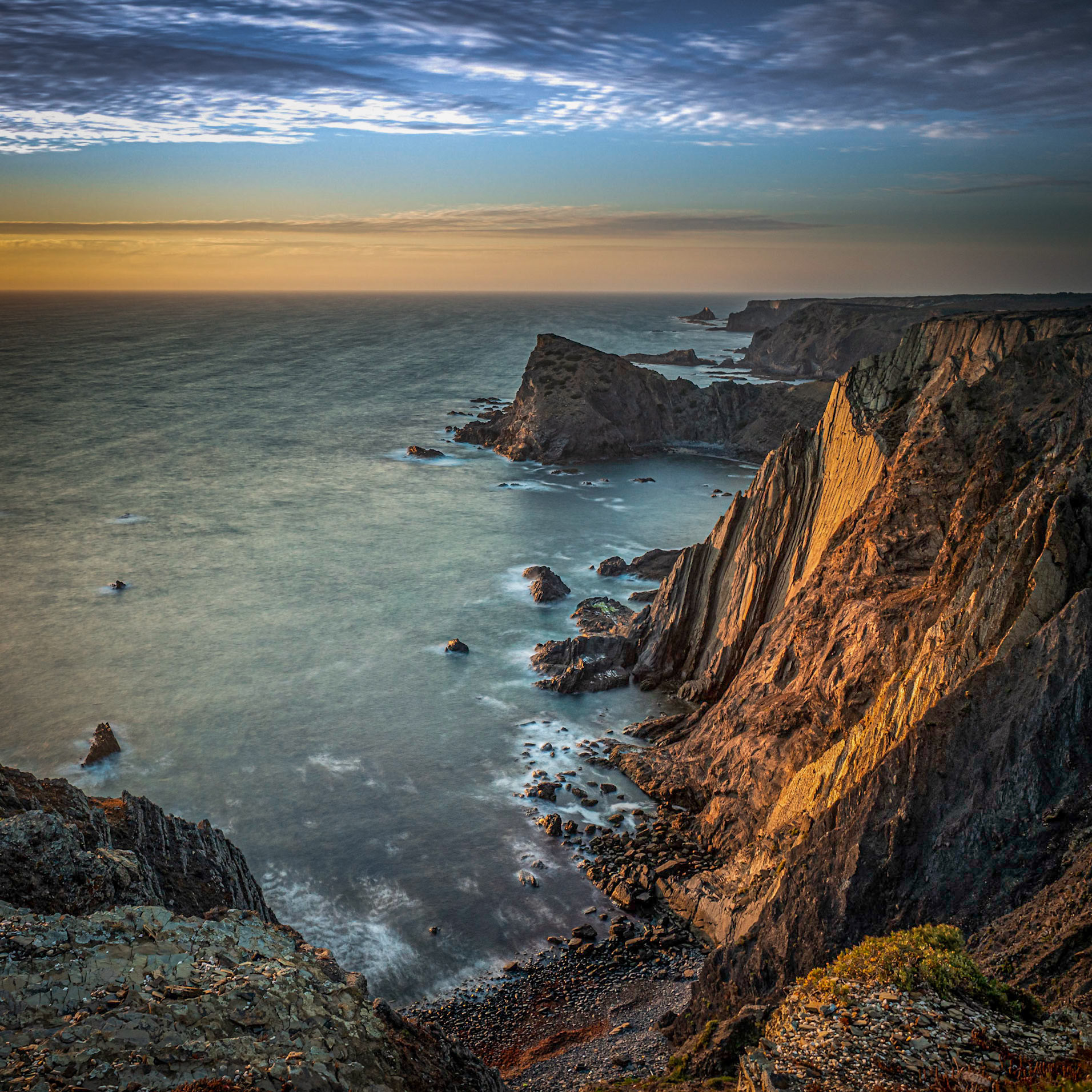 The last rays of light illuminating the seacliffs at Arrifana on the Atlantic coast of Portugal