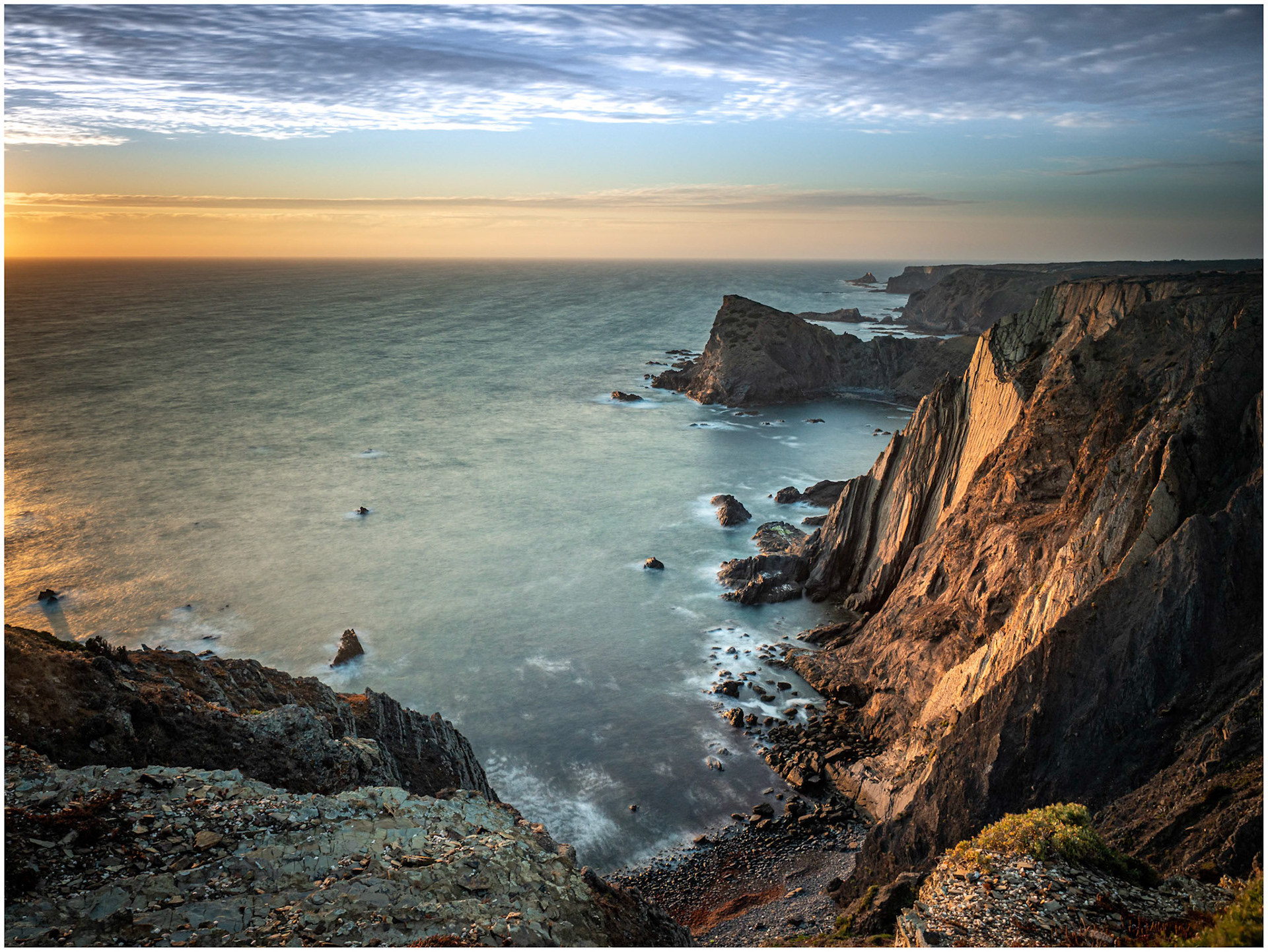 The last rays of light illuminating the seacliffs at Arrifana on the Atlantic coast of Portugal