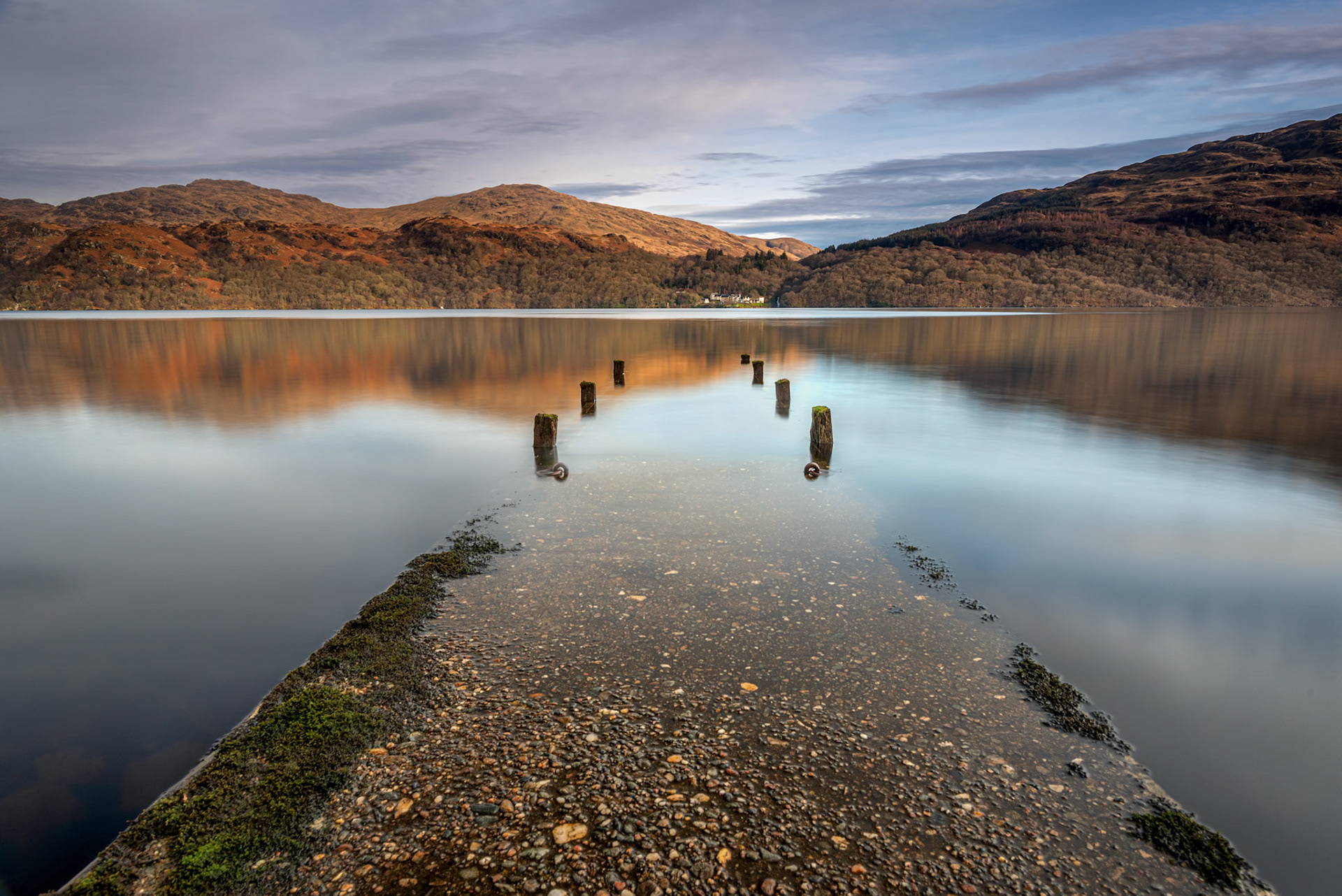A long exposure of an old jetty on the shore of Loch Lomond, Scotland.  Looking over to Inversnaid and the mountains of Loch Lomond National Park.