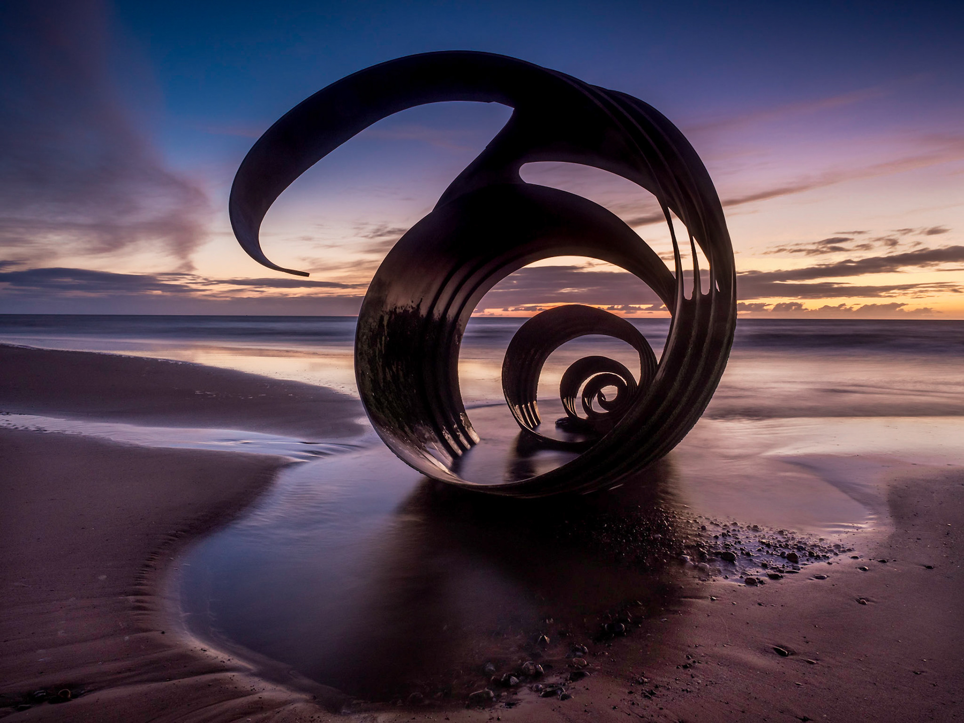 Sunset at the beach at Cleveleys on the Lancashire Coast with the artwork Mary's Shell  in the foreground