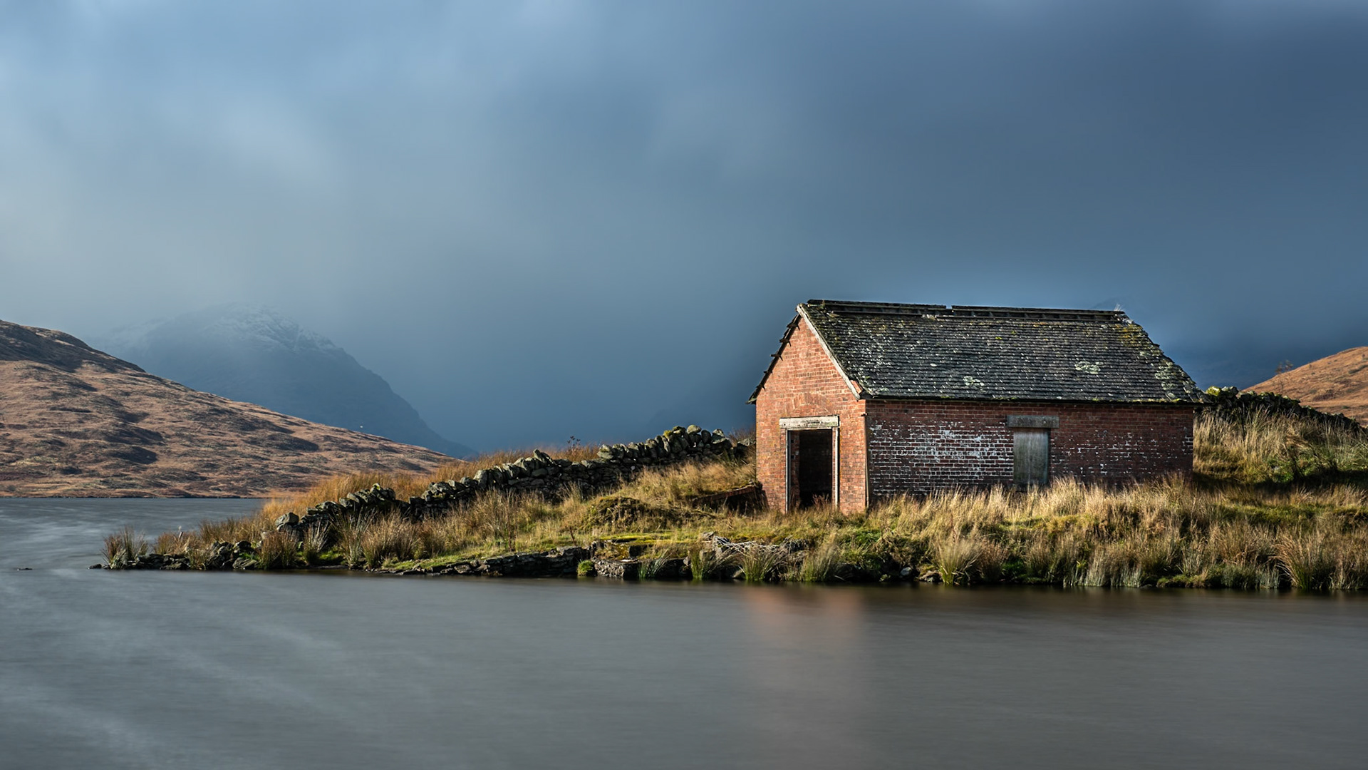 Boat house at Loch Arklet with approaching storm clouds over the Arrochar Alps, near Stronachlachar, Loch Lomond &amp; The Trossachs National Park, Scotland