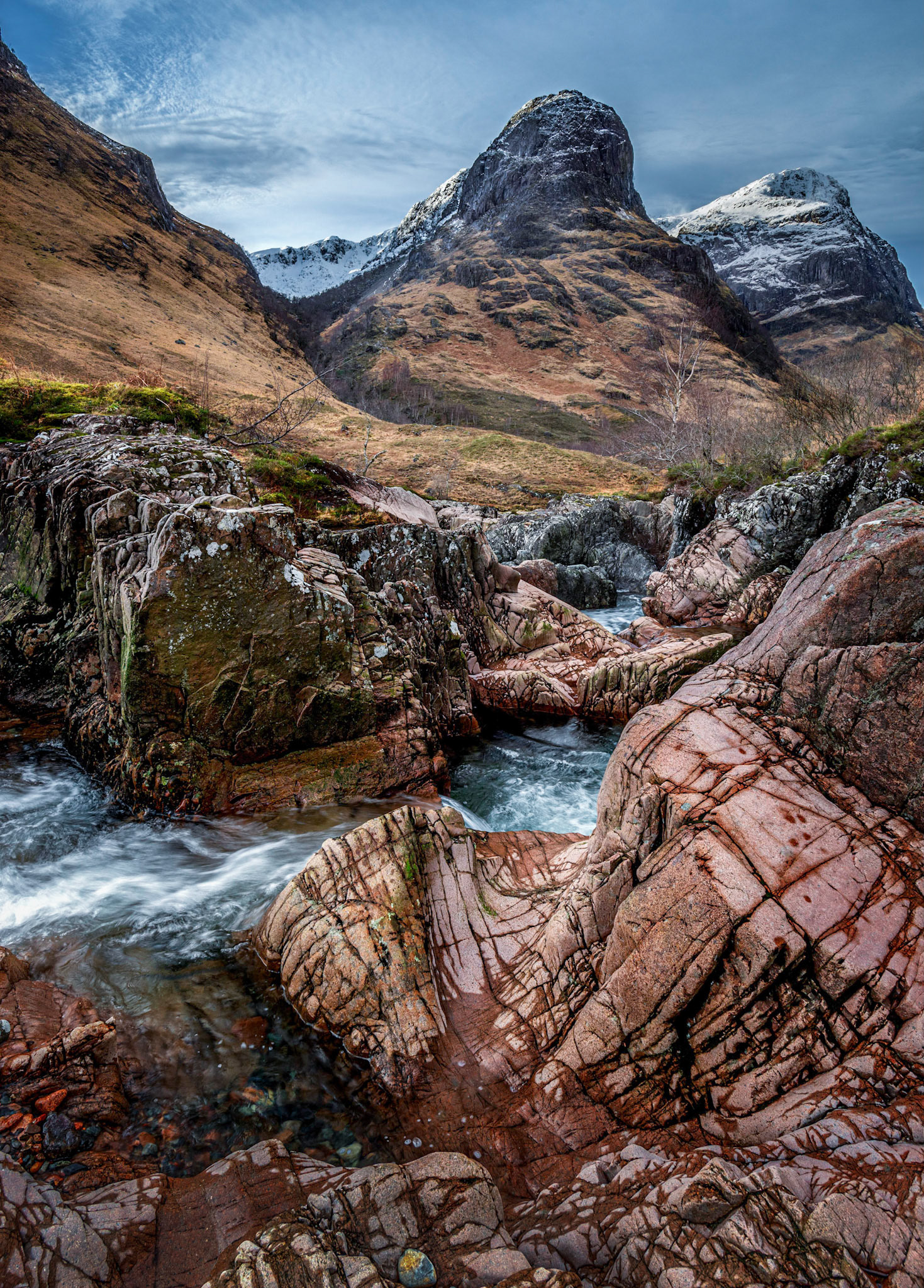 The River Coe flowing through Glen Coe  in winter with the group of mountains oknown as The Three Sisters in the background