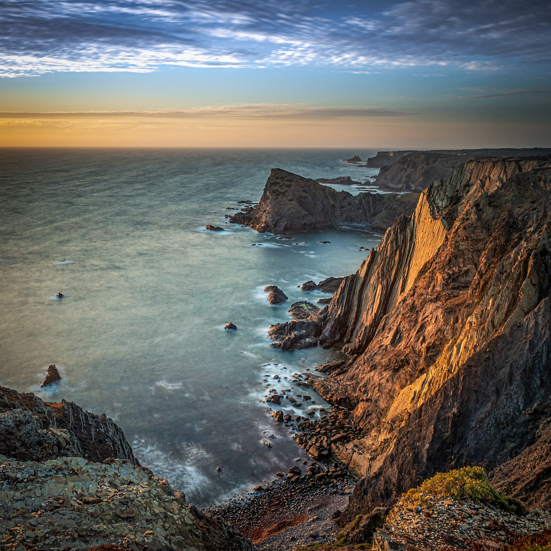 The last rays of light illuminating the seacliffs at Arrifana on the Atlantic coast of Portugal