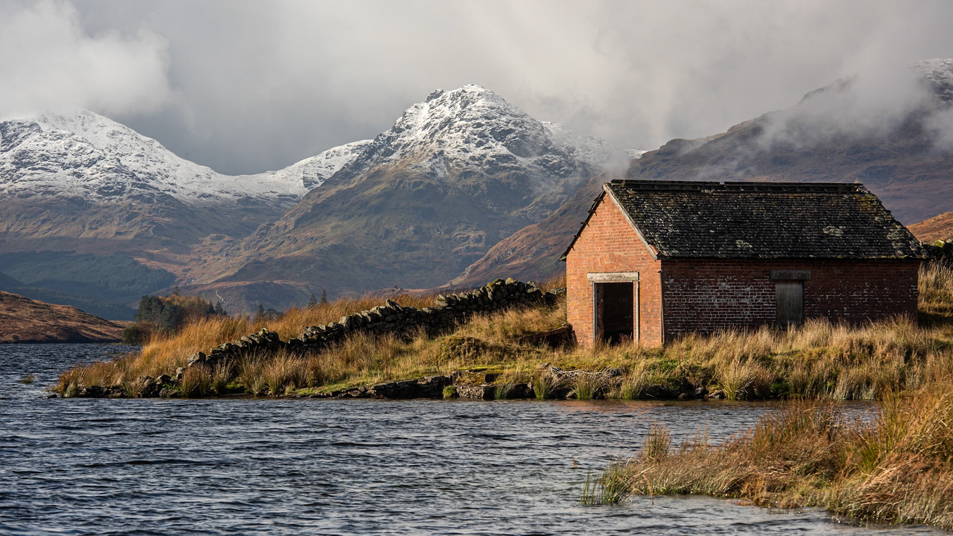 Boat house at Loch Arklet with gathering storm clouds over the Arrochar Alps, near Stronachlachar, Loch Lomond &amp; The Trossachs National Park, Scotland