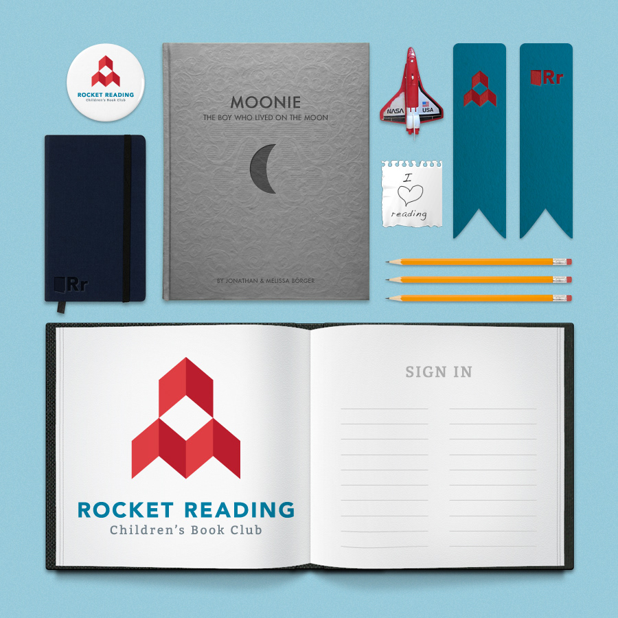 A flat lay arrangement of reading-themed items on a light blue background, including a "Rocket Reading Children's Book Club" logo and open notebook, a gray book titled "Moonie: The Boy Who Lived on the Moon," a black notebook, pencils, bookmarks, a NASA space shuttle pin, and an "I love reading" note.