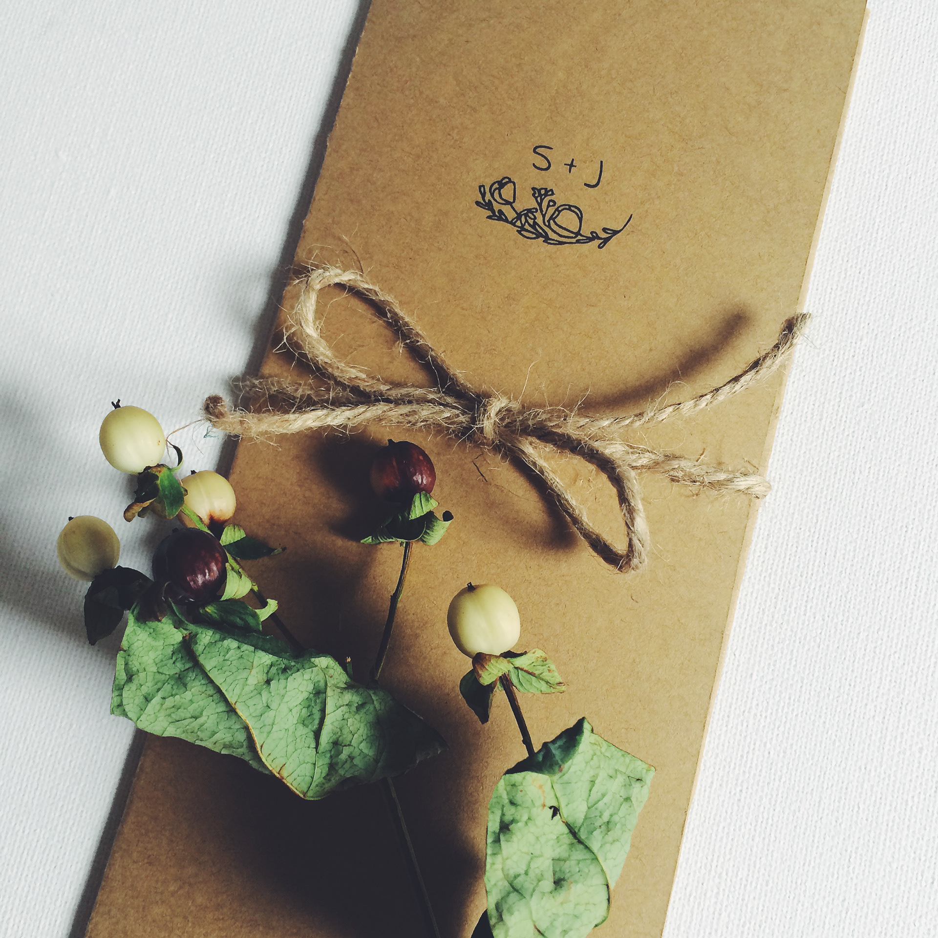 Custom invitation featuring S + J monogram and flower illustration viewed at a closeup angle