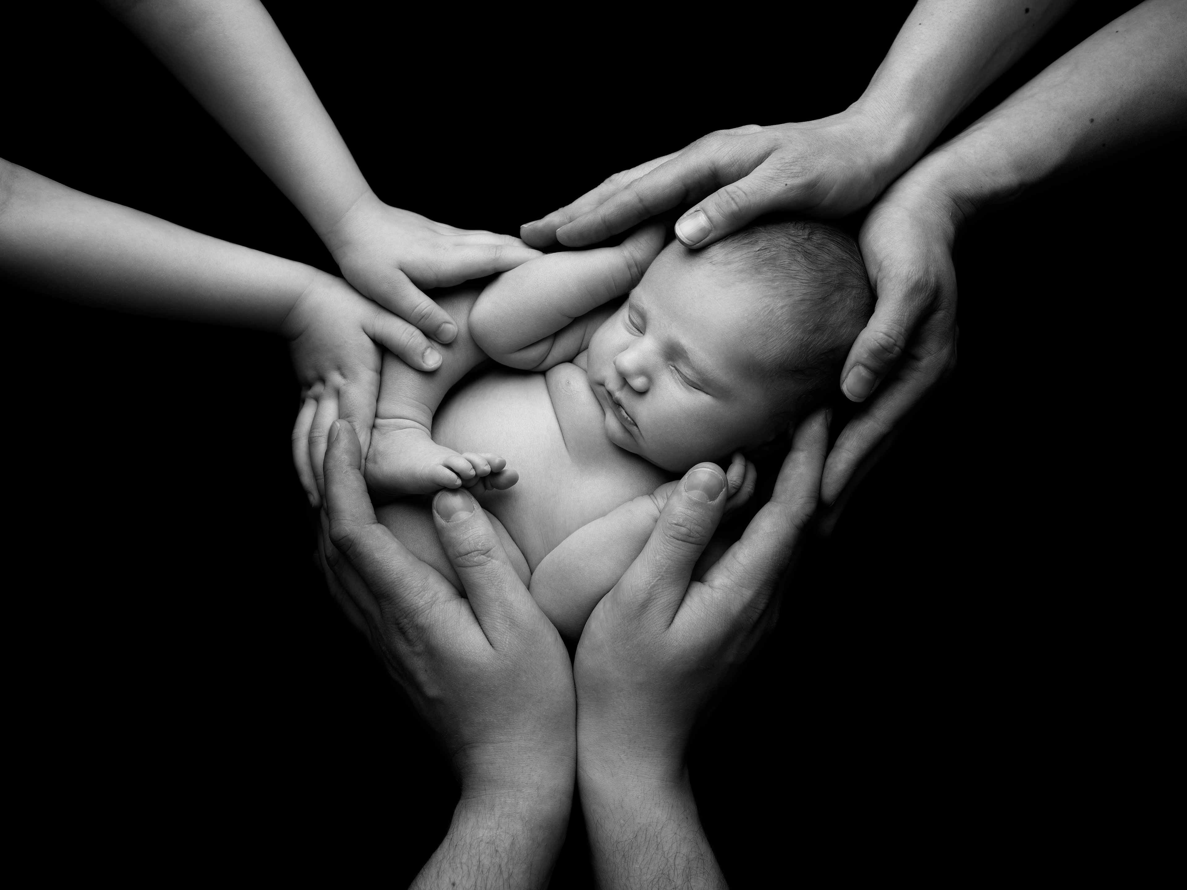 Nyfødt lillesøster i familiens hender, nyfødtfotografering hos Lille Trille Foto Tromsø